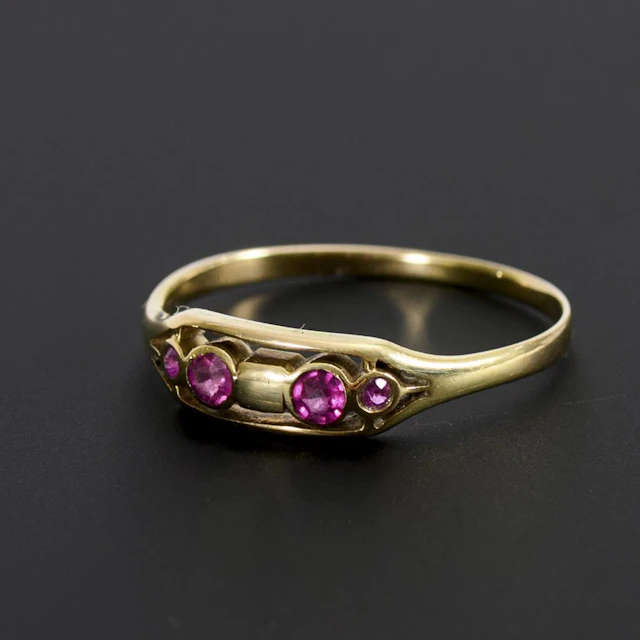 Delicate Art Nouveau ring with small red gemstones or synthetic stones.