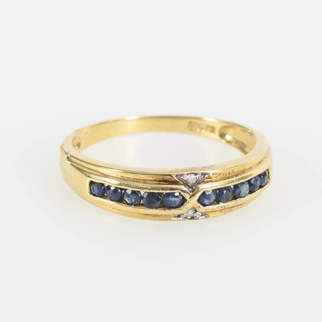 Band ring with blue gemstones, likely sapphires, and diamonds.