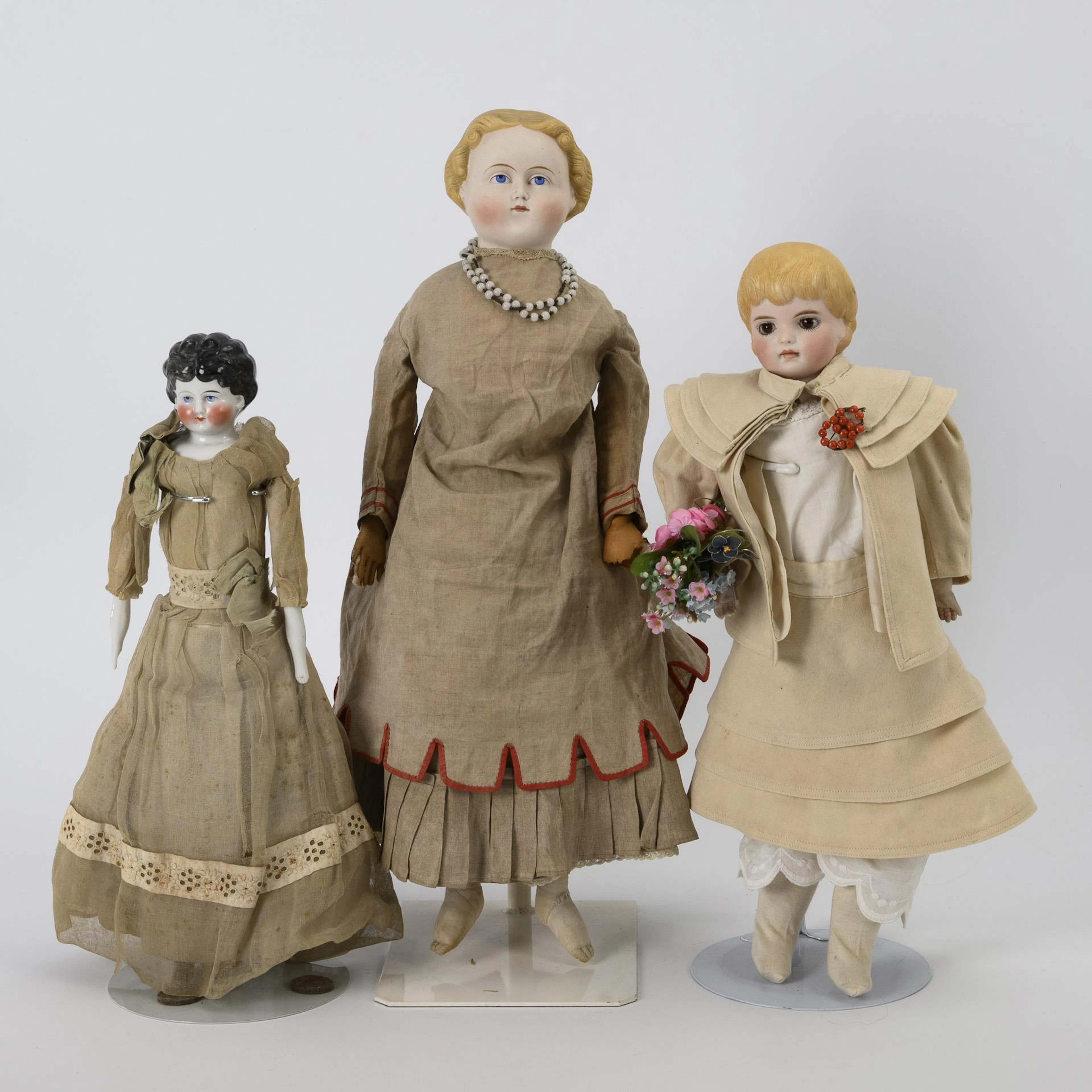 3 chest head dolls in beige dresses.