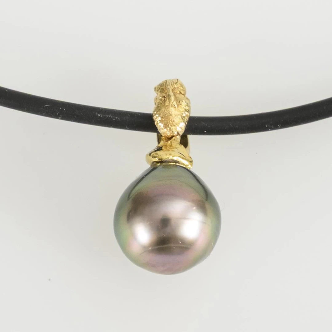 Pendant with a dark pearl on a rubber cord.