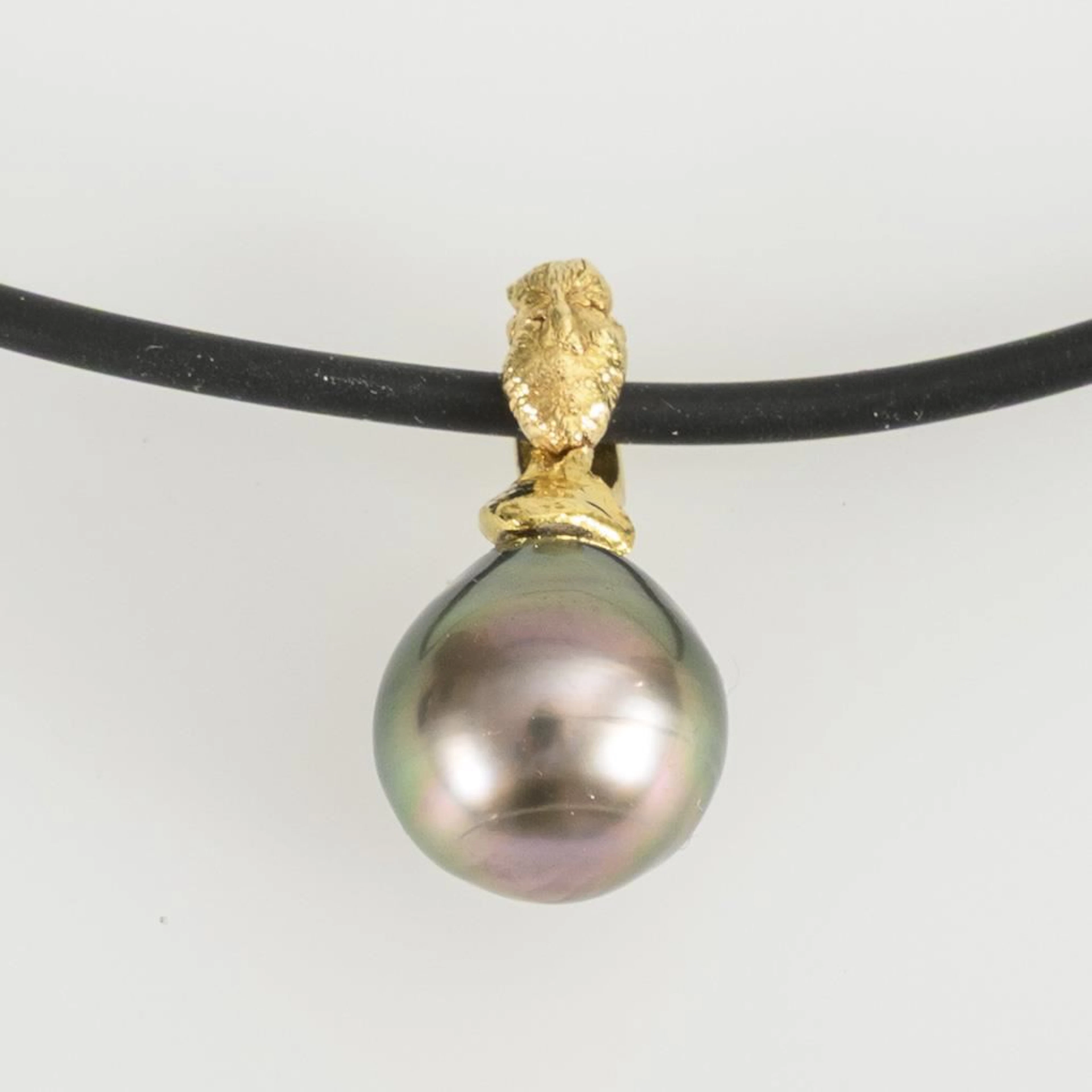 Pendant with a dark pearl on a rubber cord.