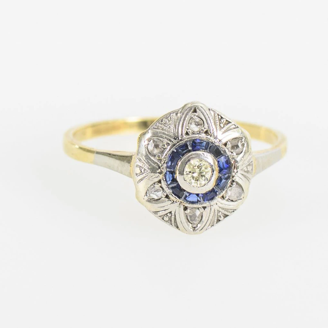 Round Art Deco ring with blue gemstones and a brilliant-cut diamond.
