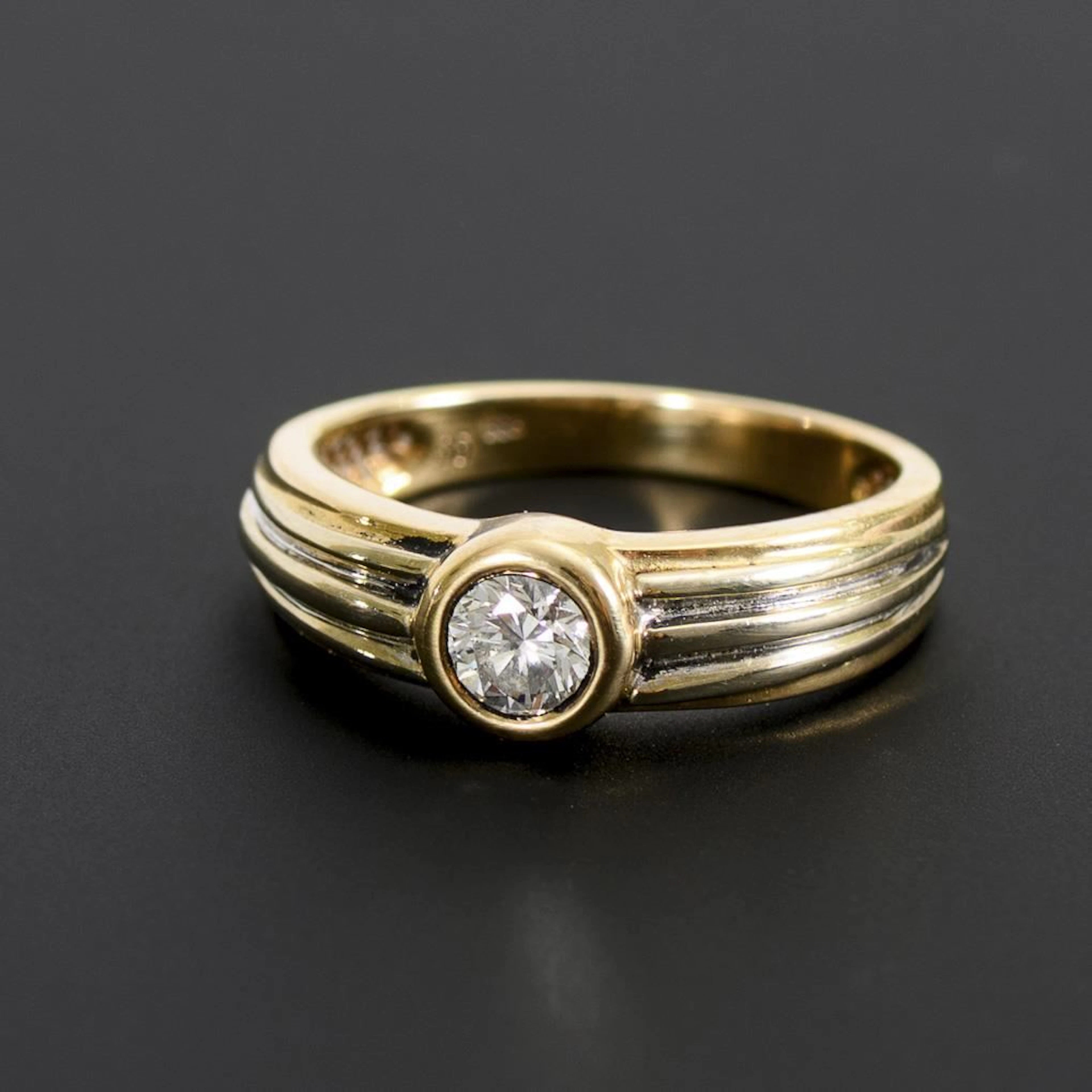 Band ring with a solitaire brilliant-cut diamond.