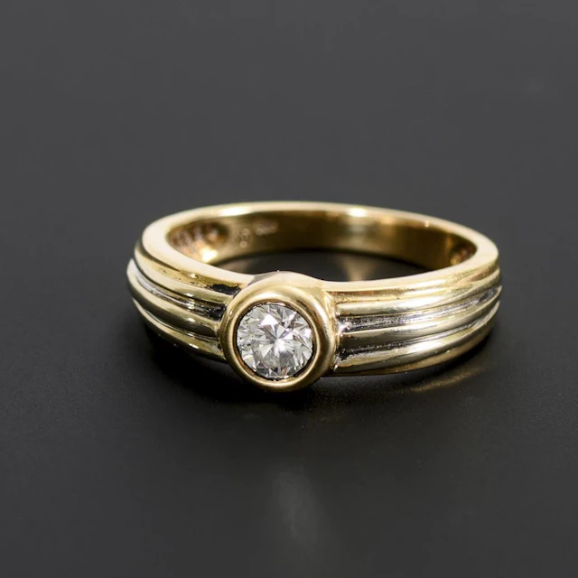 Band ring with a solitaire brilliant-cut diamond.