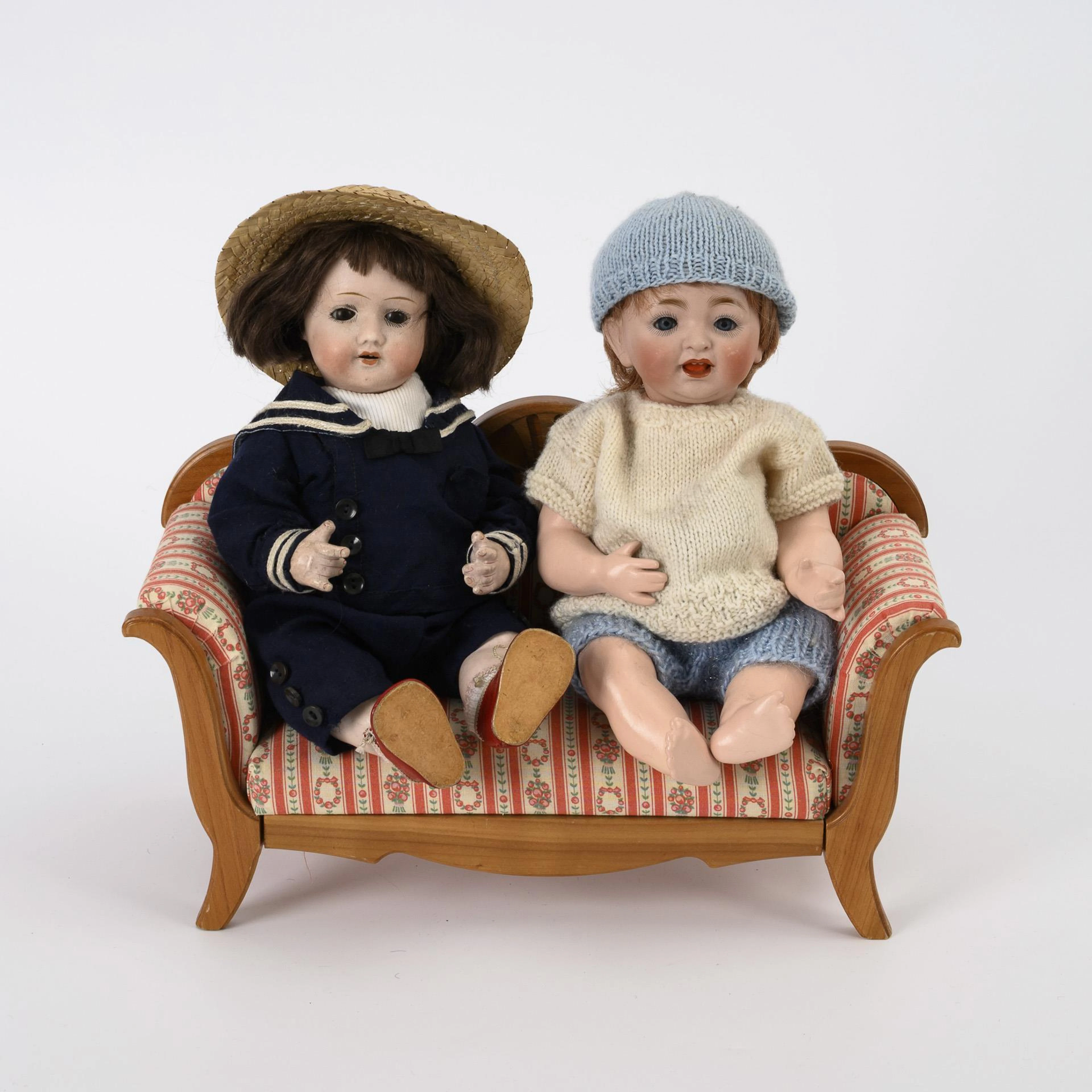 2 small dolls on sofa.