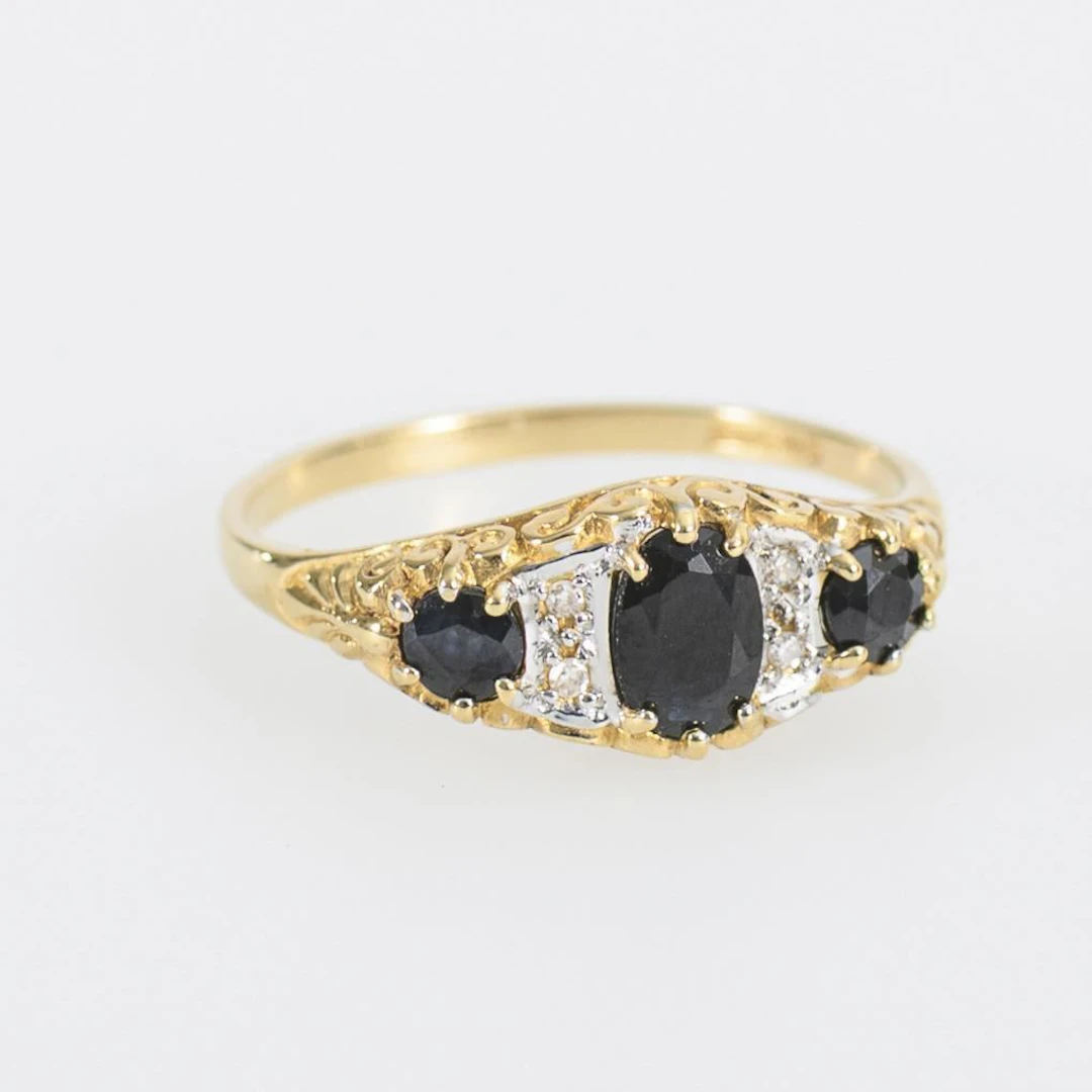 Ring with 3 blue gemstones, likely sapphires.