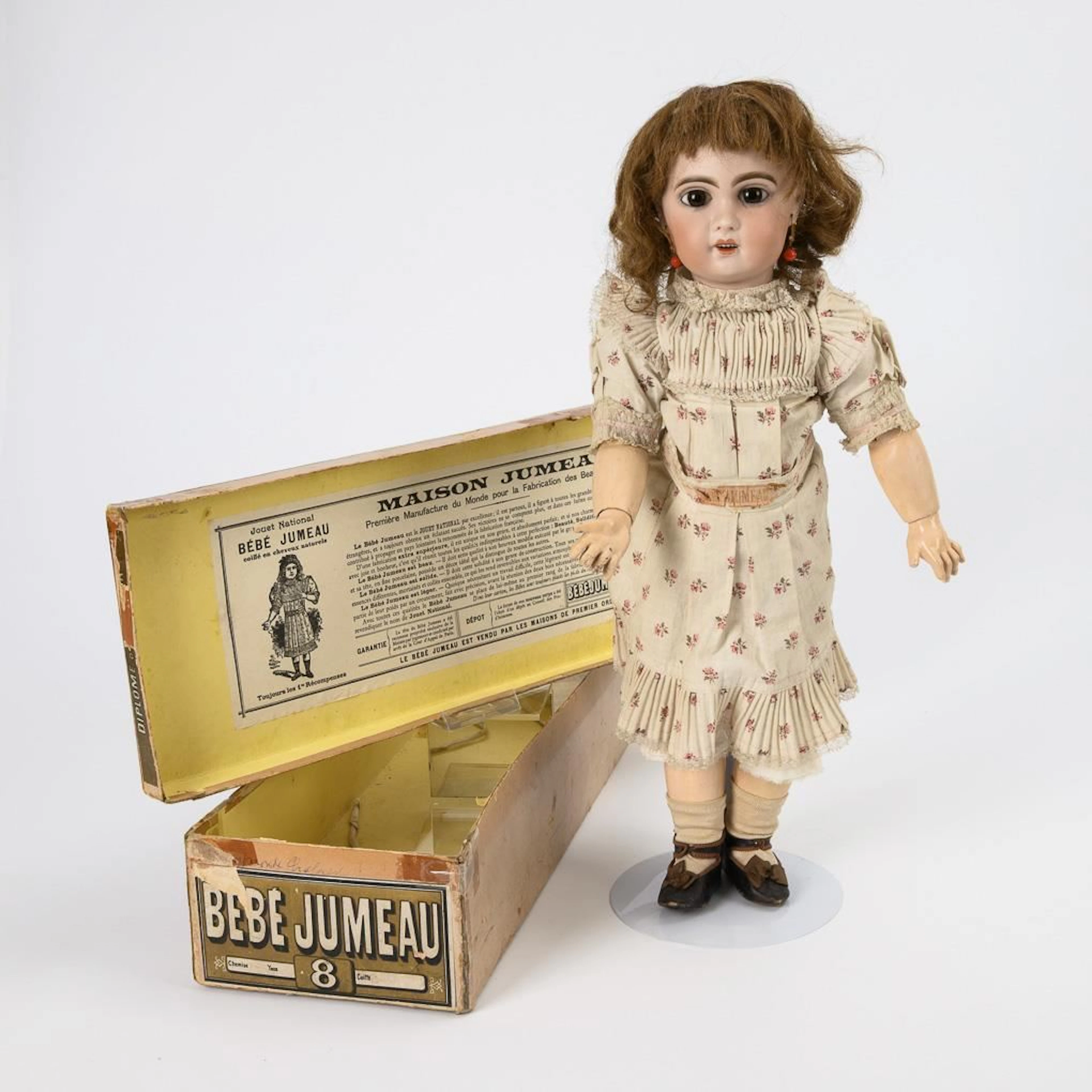 "Bébé Jumeau" doll in original clothing, packaged in a cardboard box.