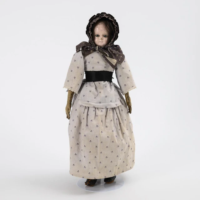 Chest-head doll with a gray bonnet.