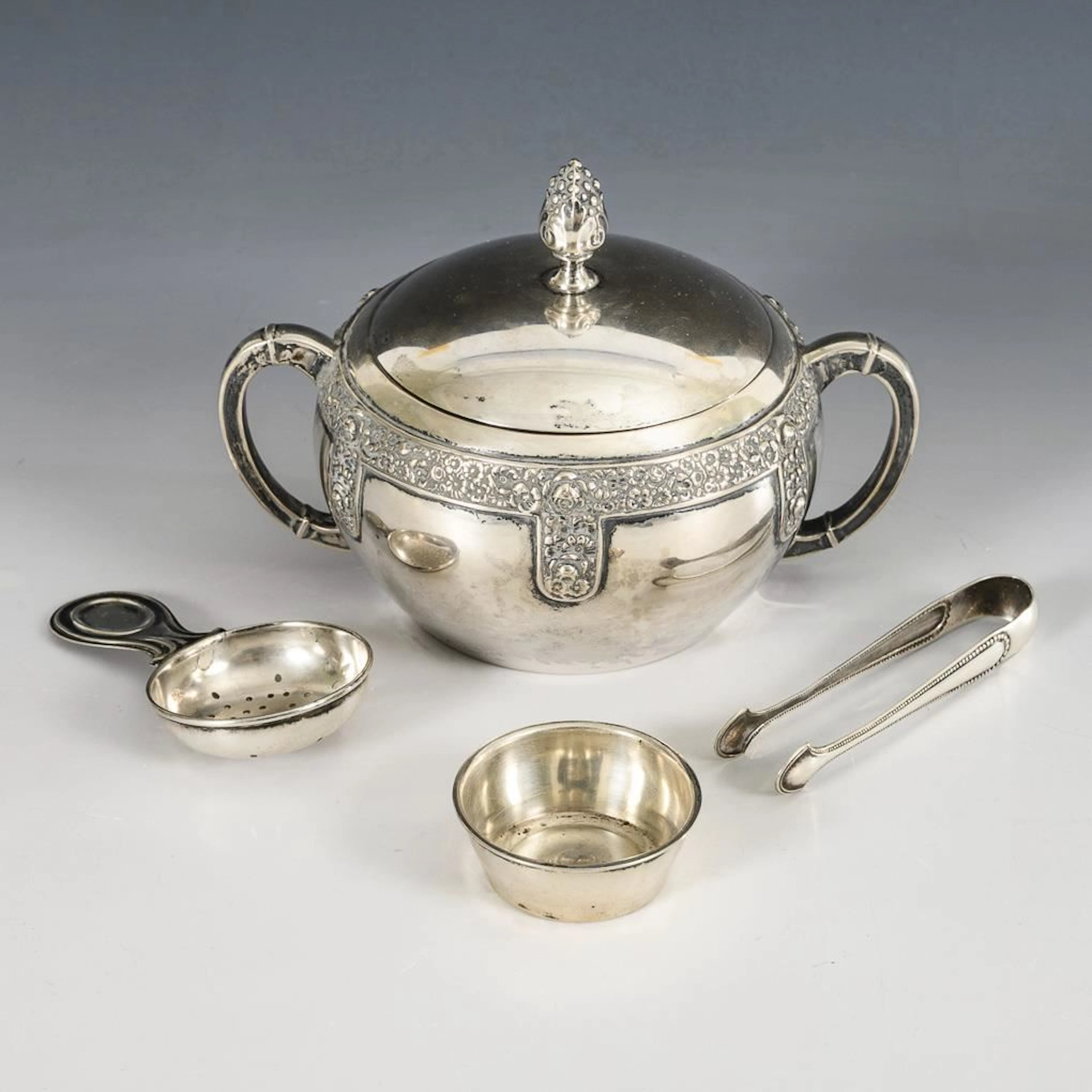 Sugar bowl, sugar tongs, and tea strainer.