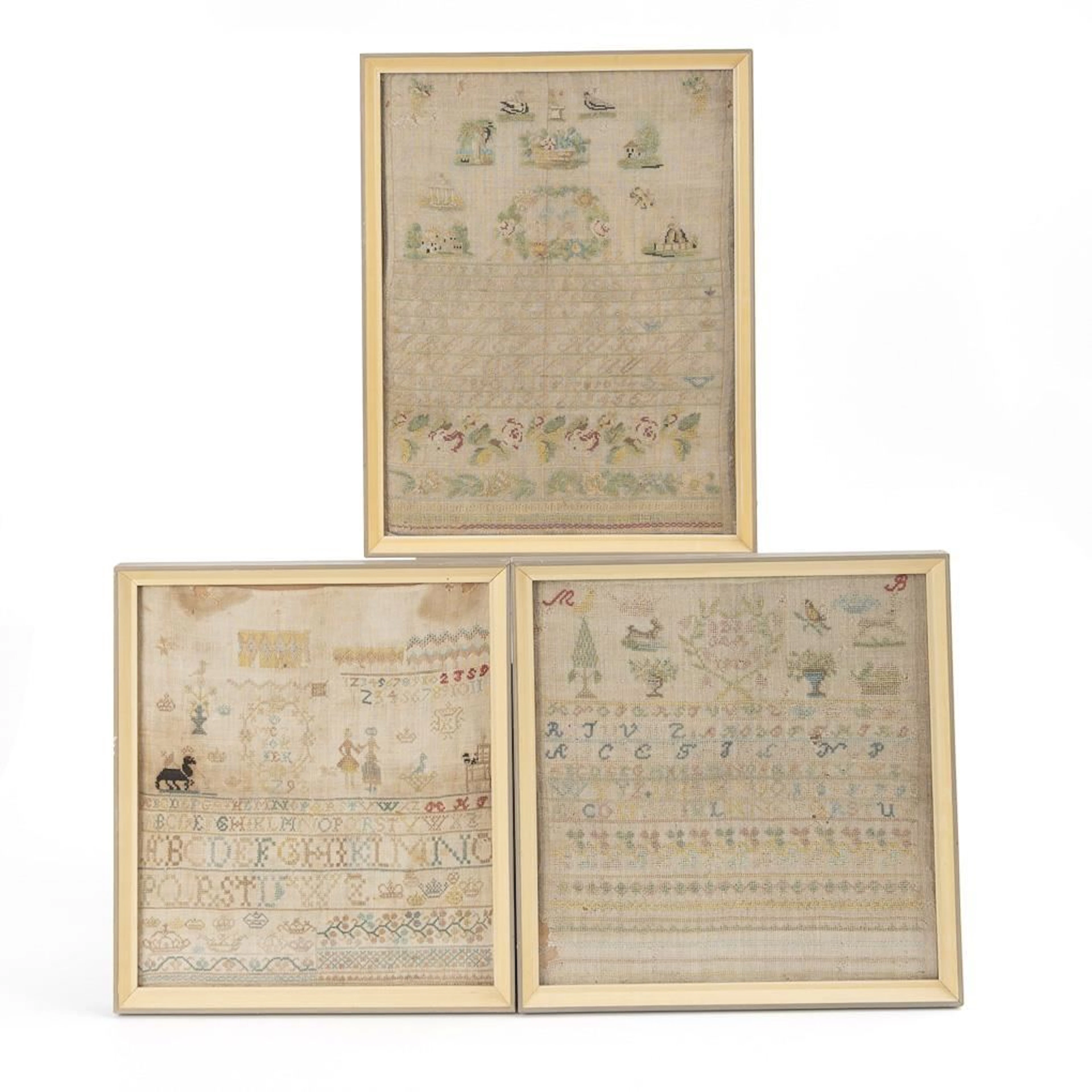 Three framed embroidery samplers.