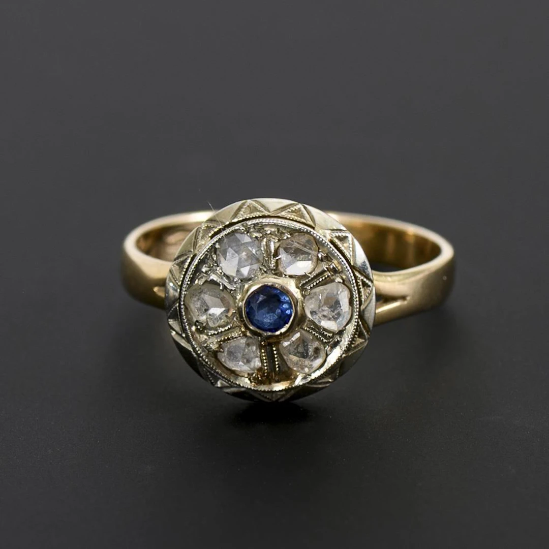 Ring with a round band, a blue gemstone, and rose-cut diamonds.