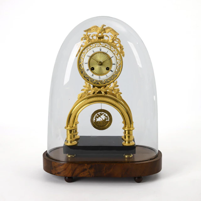 Pompous Empire skeleton clock with eagle crown and glass dome.