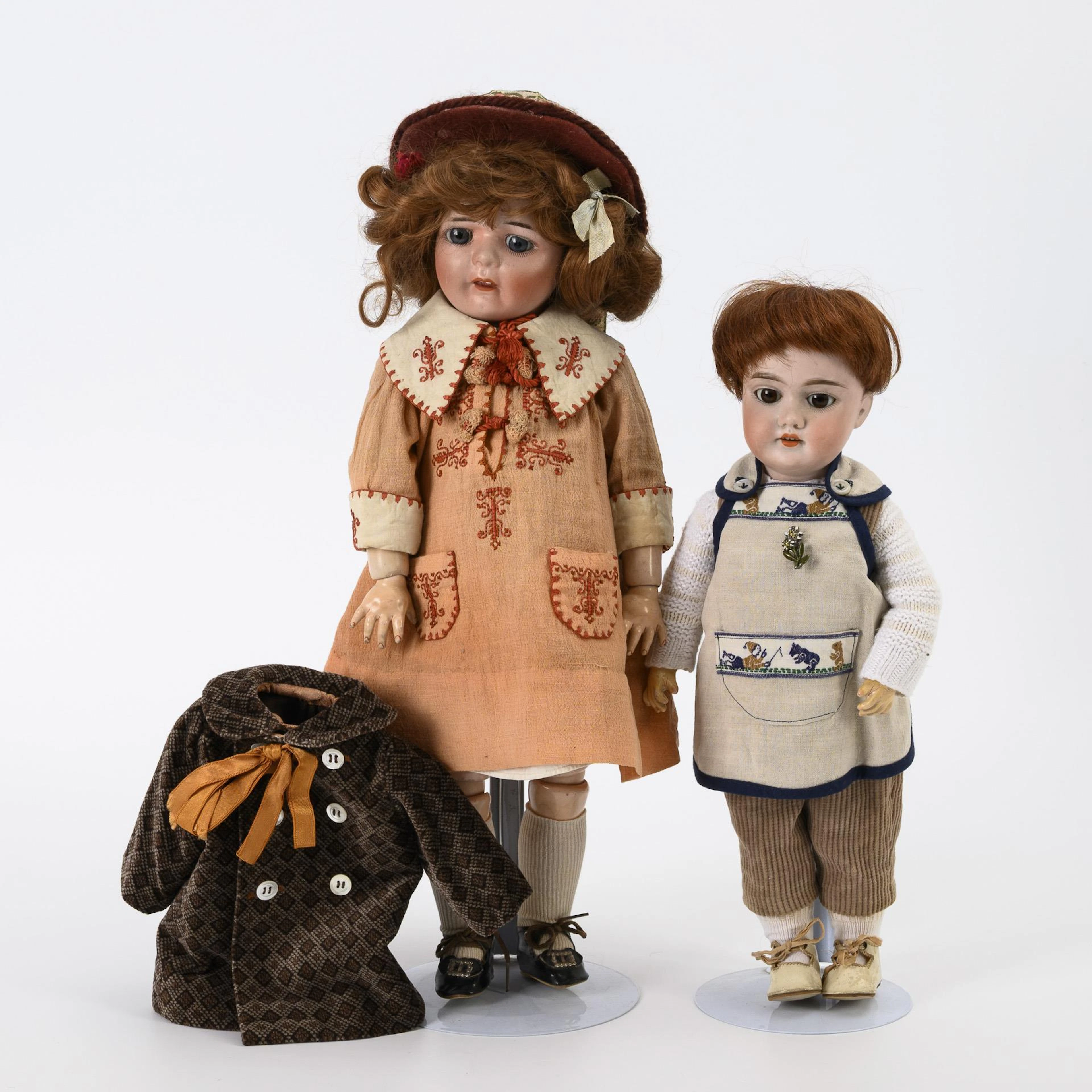 2 porcelain head dolls with reddish-brown hair.