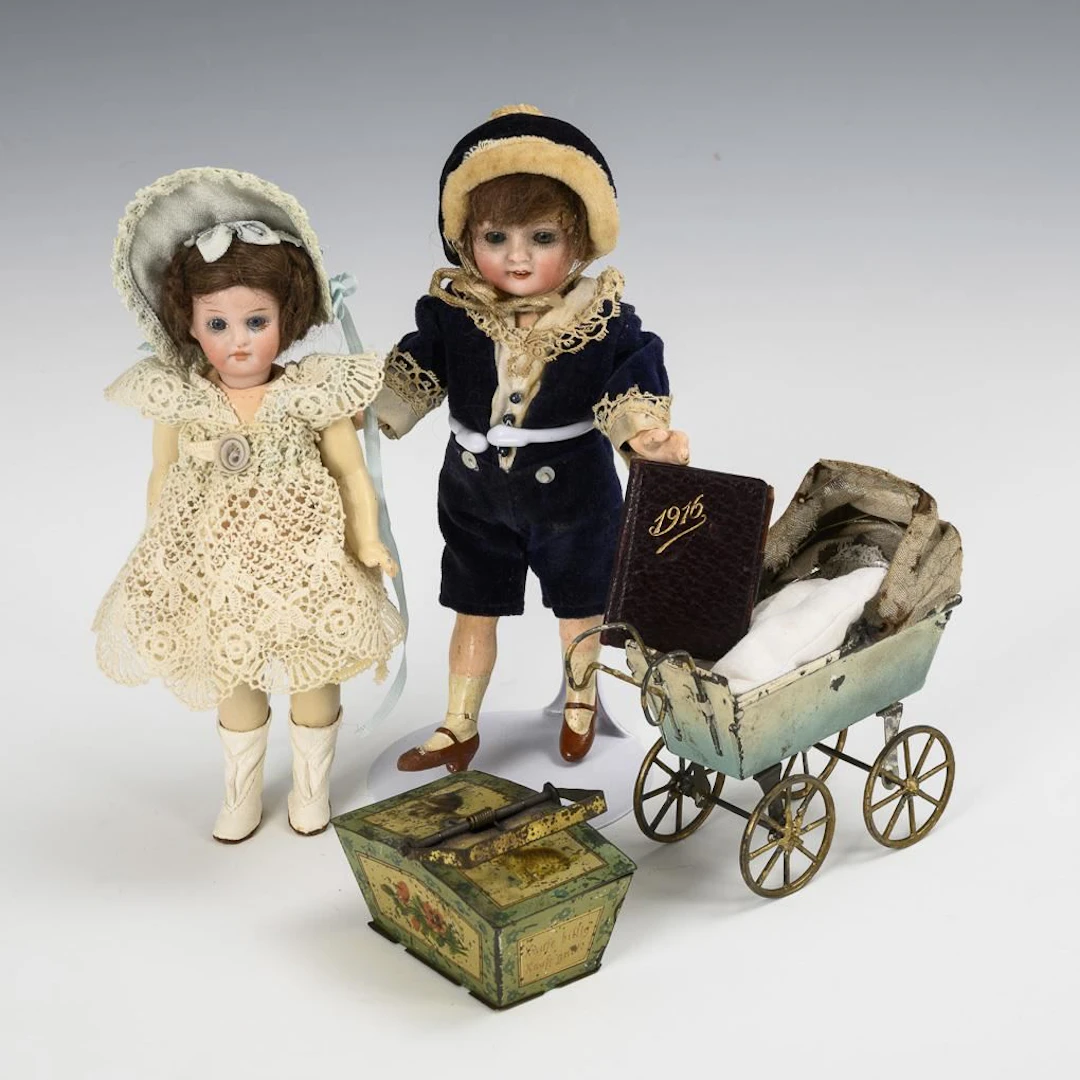 2 little dolls with glass eyes, a doll carriage, a tin basket, and