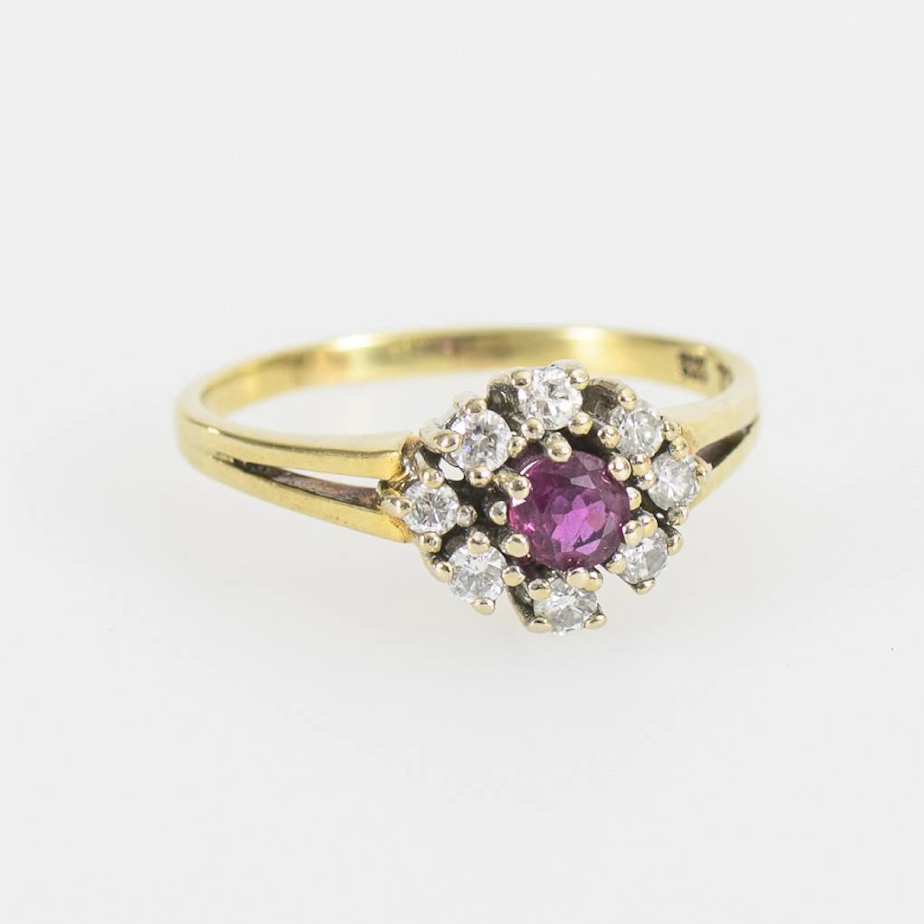 Daisy ring with a red gemstone—likely a ruby—and brilliant-cut diamonds.