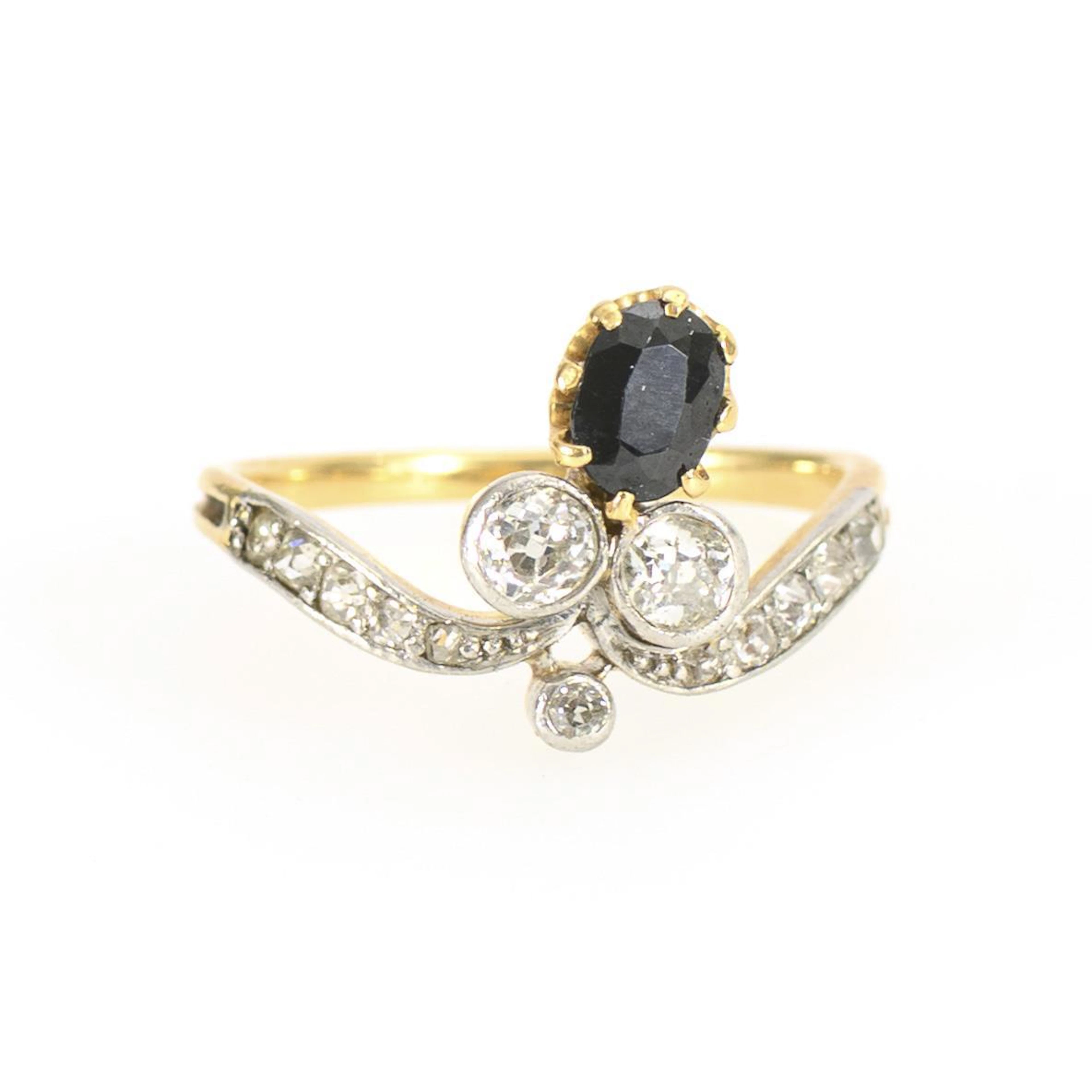 Ring with dark colored stone, probably sapphire, and old-cut diamonds.