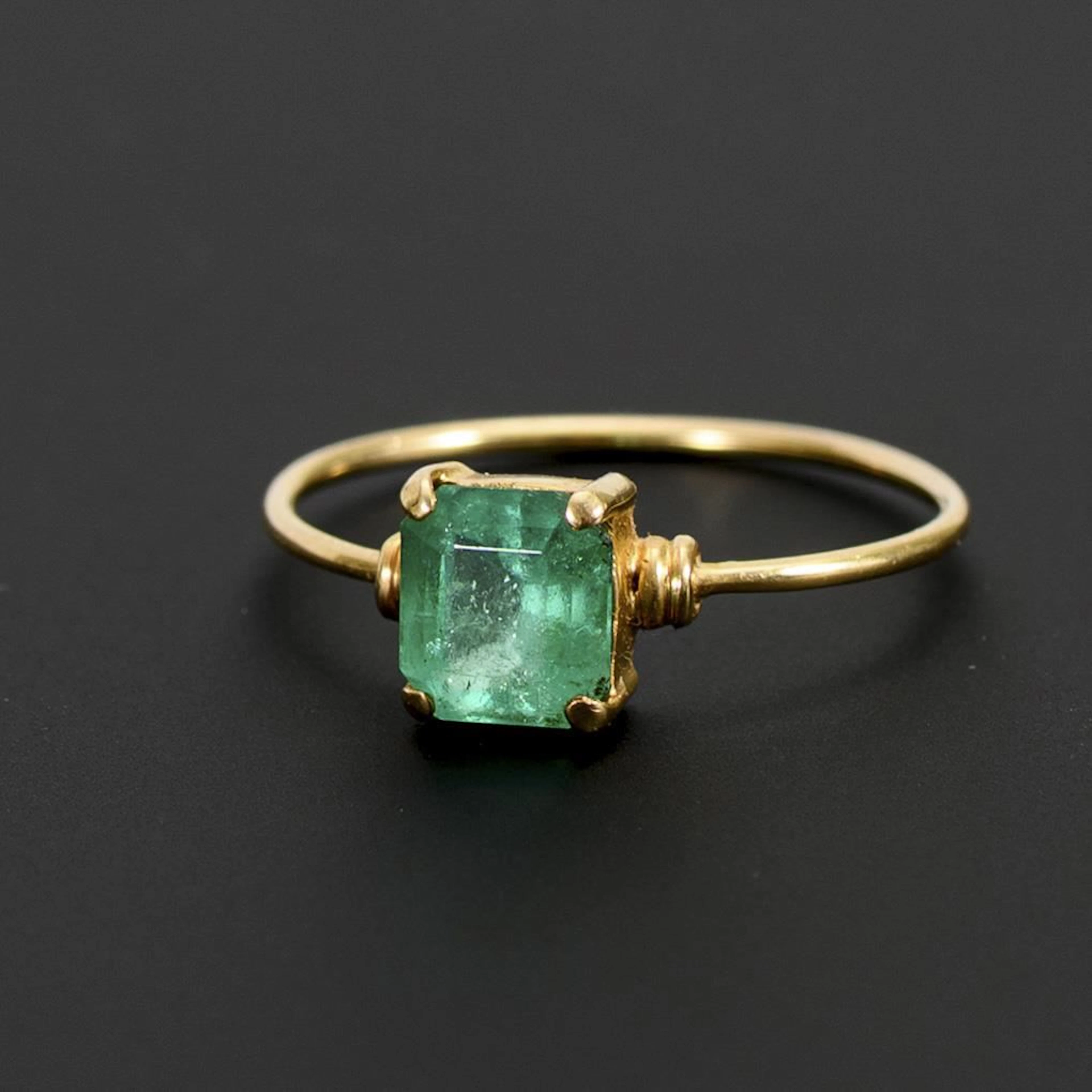 Delicate ring with a green gemstone, likely an emerald.