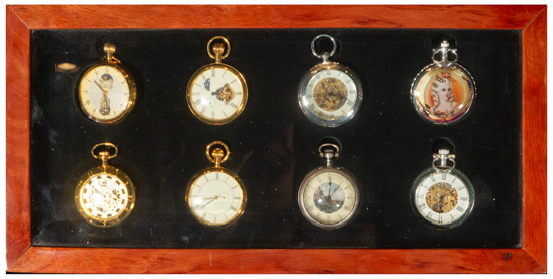 Collection of eight pocket watches in a wooden display case