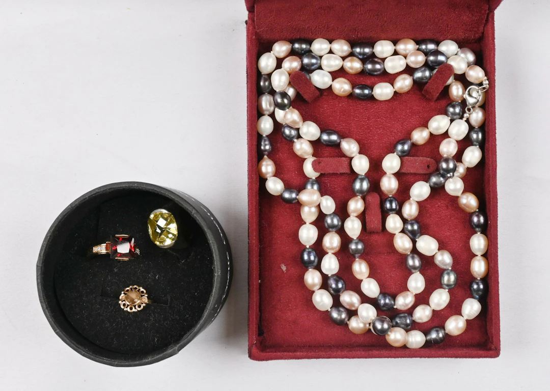 Small selection eg. pearl necklace and three rings, one of which is gold.