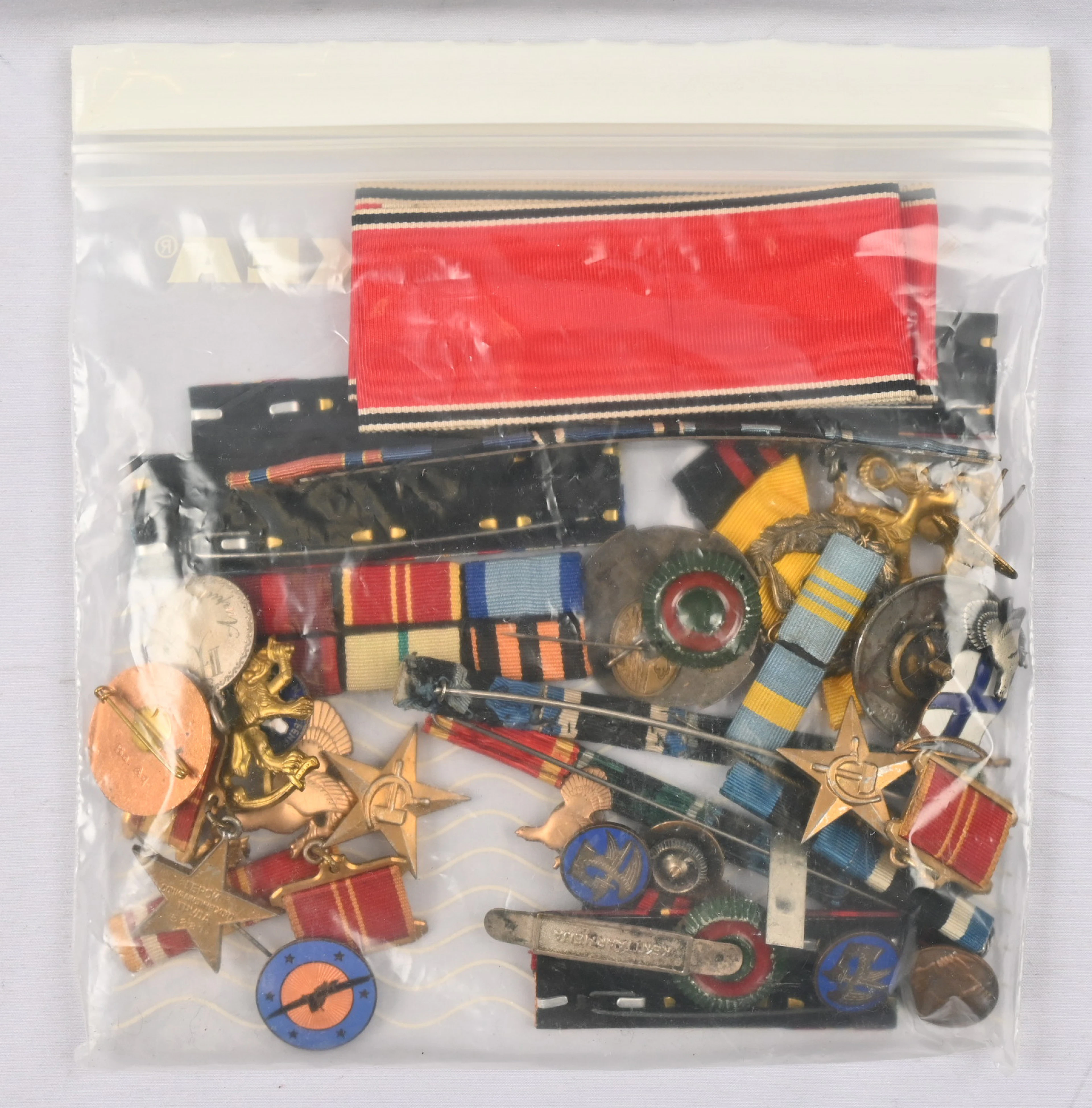 Mixed selection of pins, bars, emblems and other military-related material.