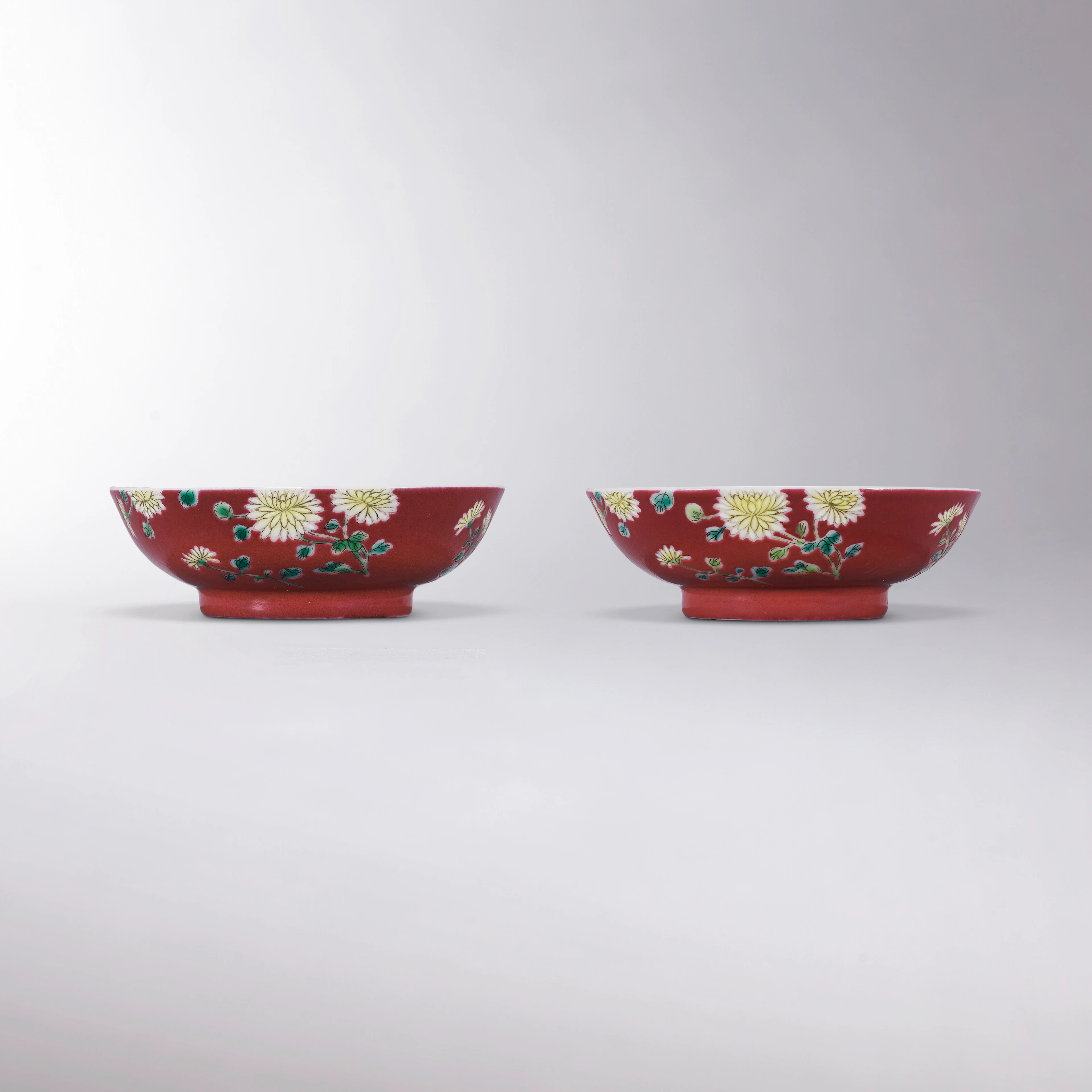 A RARE PAIR OF SMALL FALANGCAI RUBY-RED GROUND 'CHRYSANTHEMUM' DISHES