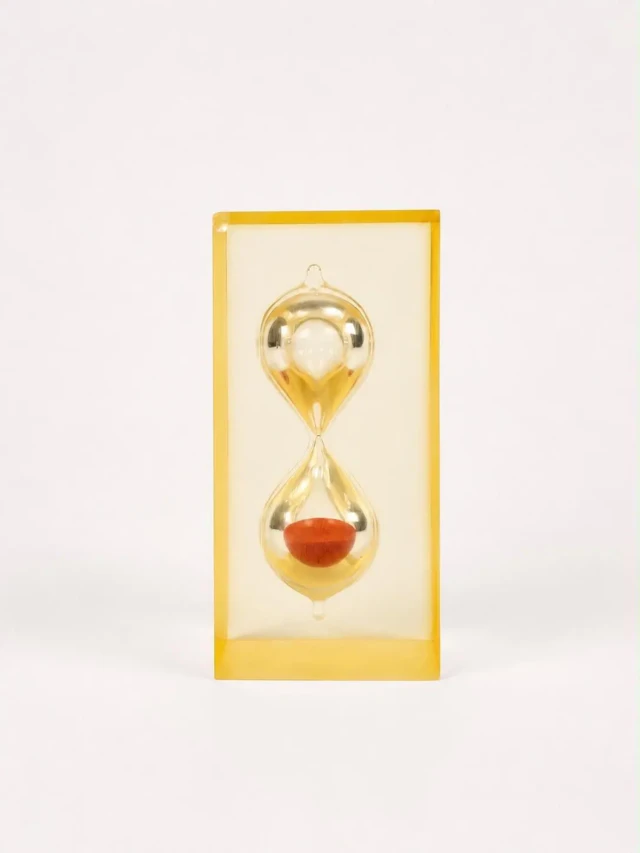 Glass hourglass in a yellow-tinted resin casing - Lot 189