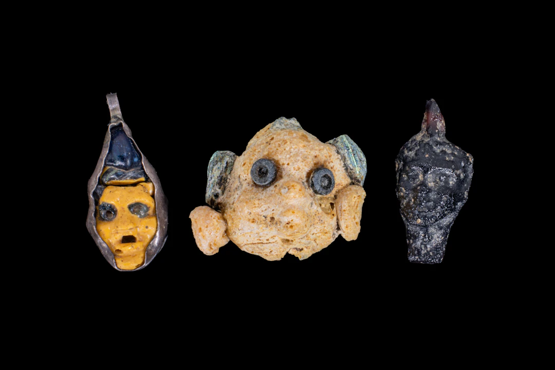 COLLECTION OF PHOENICIAN AND ROMAN GLASS FACE PENDANTS