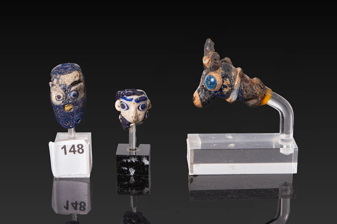 COLLECTION OF RARE PHOENICIAN GLASS HUMAN AND ANIMAL HEAD BEADS