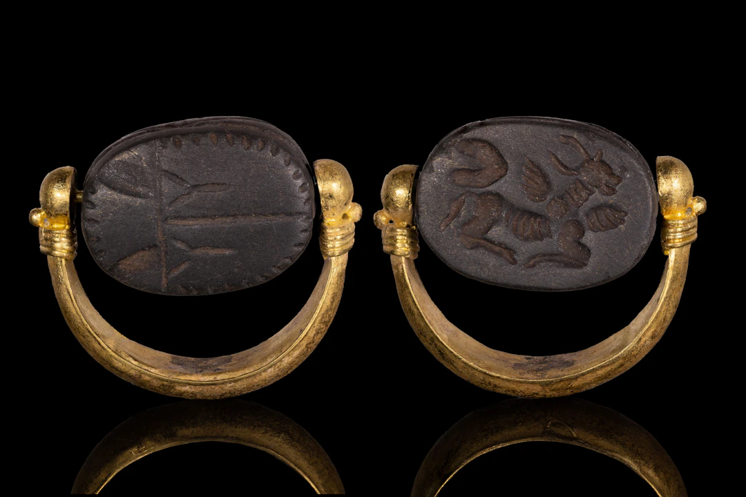 PHOENICIAN BLACK STONE SCARABOID WITH WINGED BULL IN GOLD SWIVEL RING