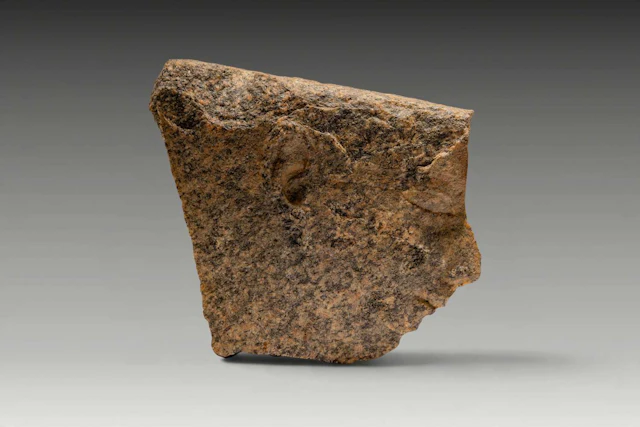 EGYPTIAN GRANITE RELIEF FRAGMENT DEPICTING A MALE HEAD