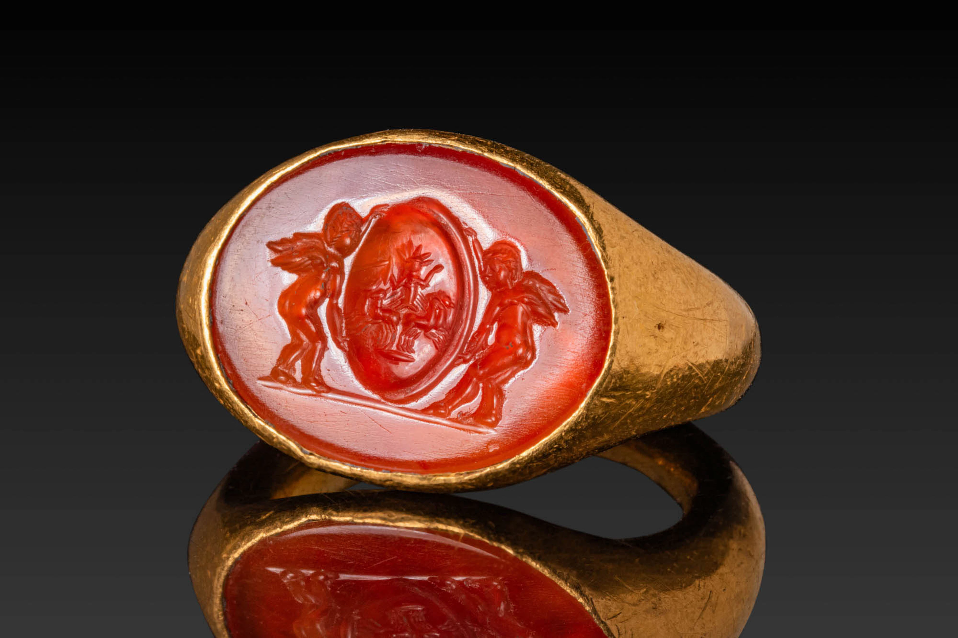 ROMAN HIGH KARAT GOLD RING WITH CARNELIAN INTAGLIO DEPICTING EROTES