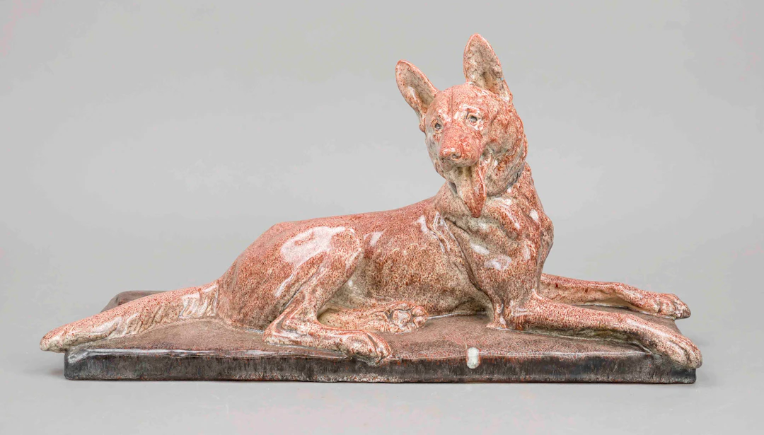 Liegender Schäferhund auf Plinthe