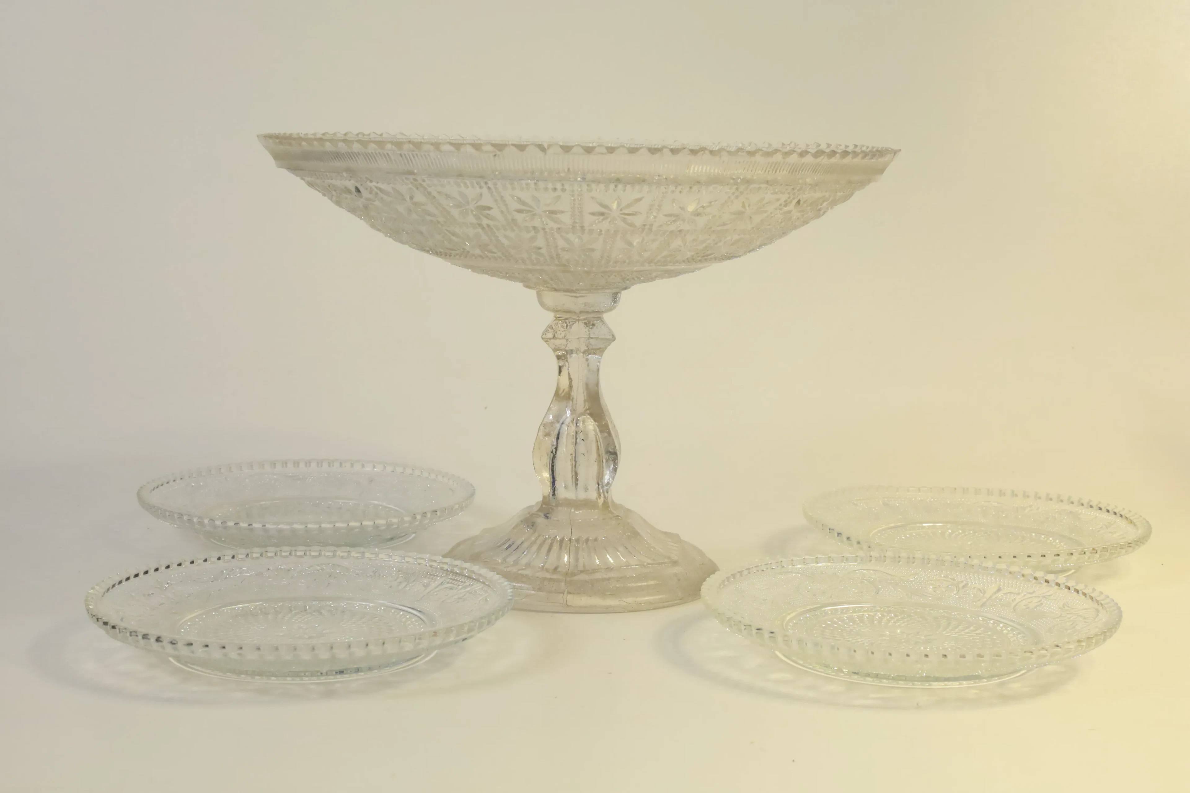 SKÅL PÅ FOT SAMT ASSIETTER, 5 delar, pressglas, 1900-talets första hälft.