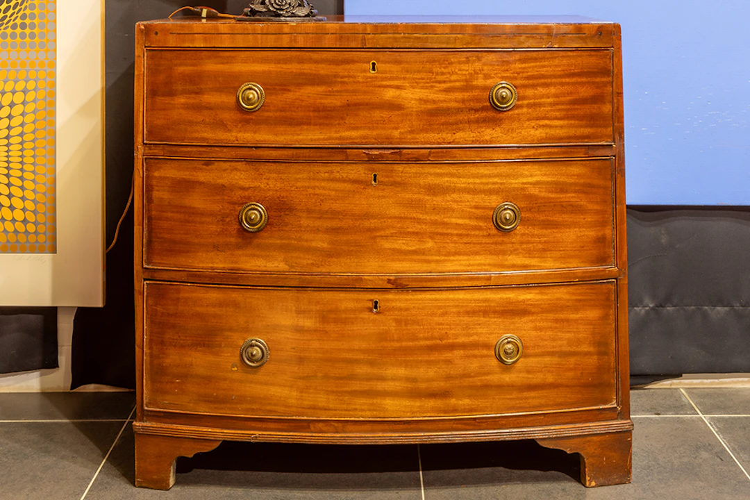 Antieke Engelse commode met gegalbeerd front in acajou met drie laden