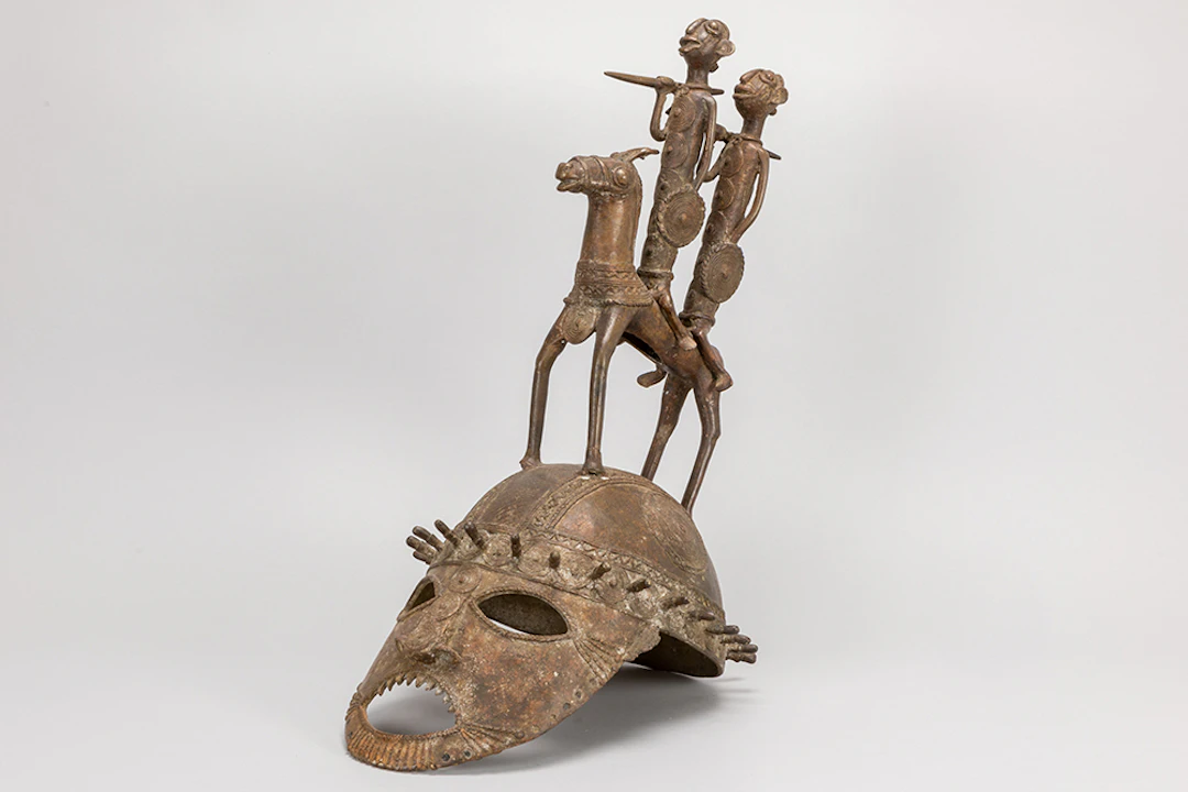 Afrikaanse sculptuur in brons met helmvorm bekroond met figuren -