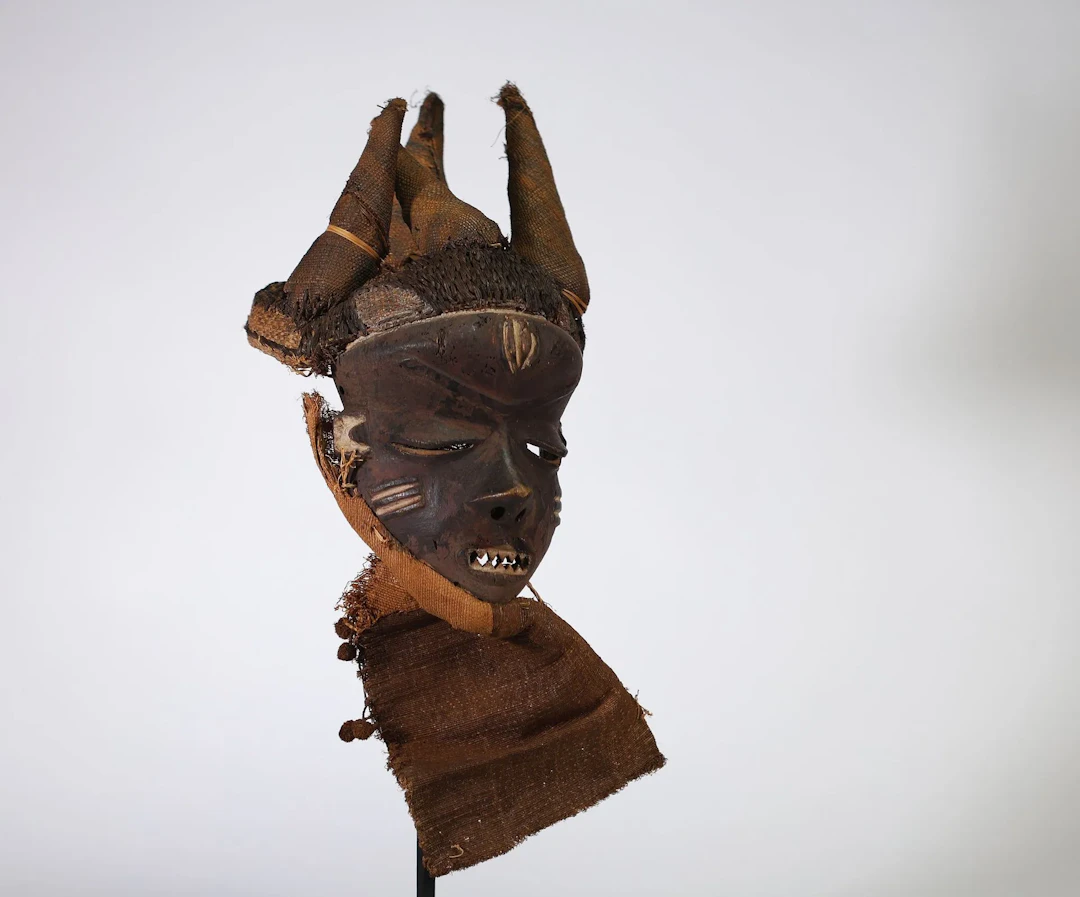 R.D.C. — PENDE — Masque en bois sculpté à patine brun foncé, - Lot 256