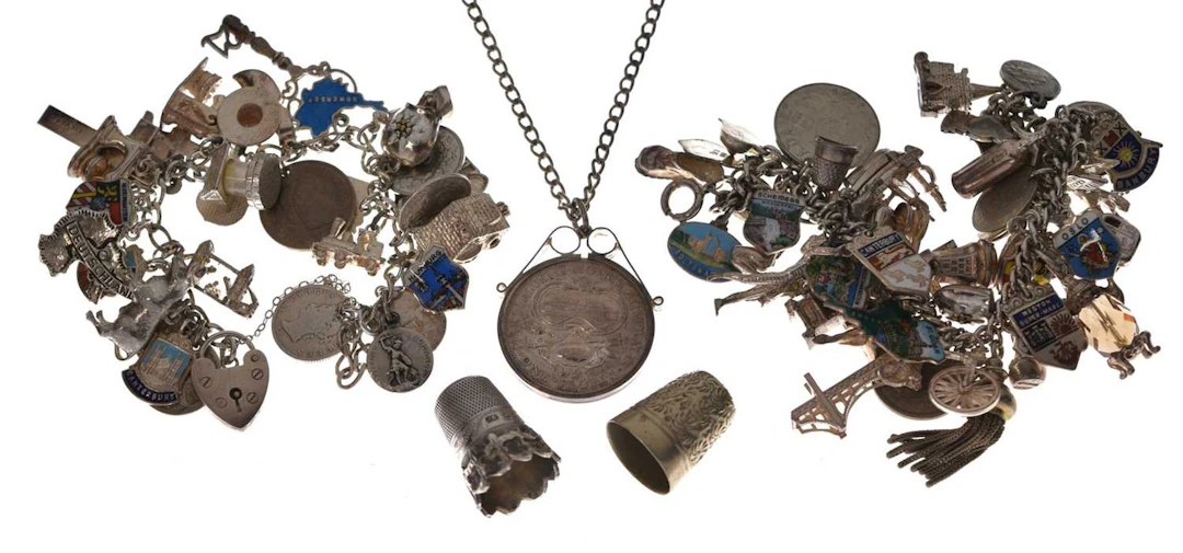 Two silver charm bracelets, two thimbles, and a mounted Australian