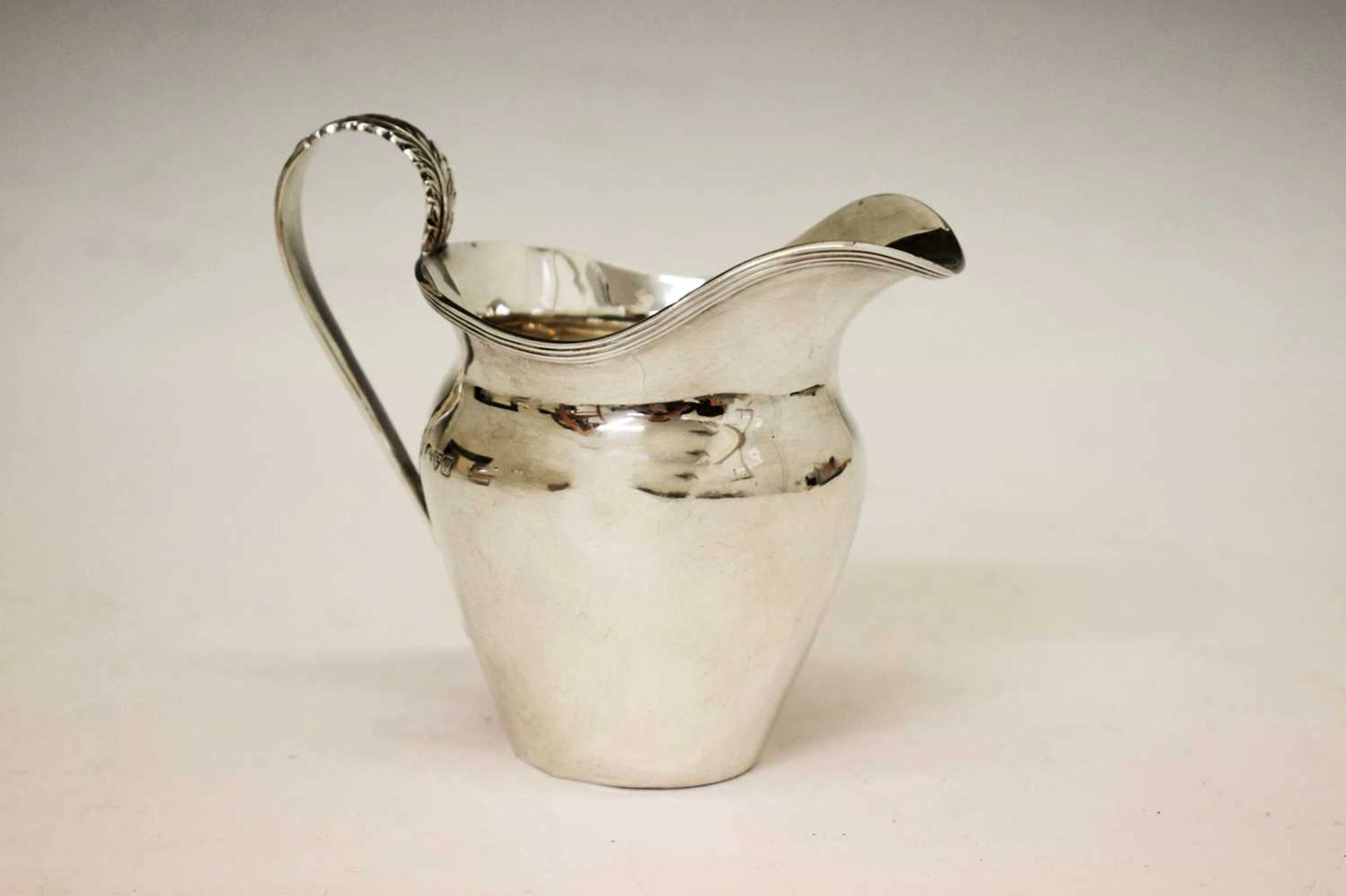 George V silver milk jug with acanthus-topped scroll handle