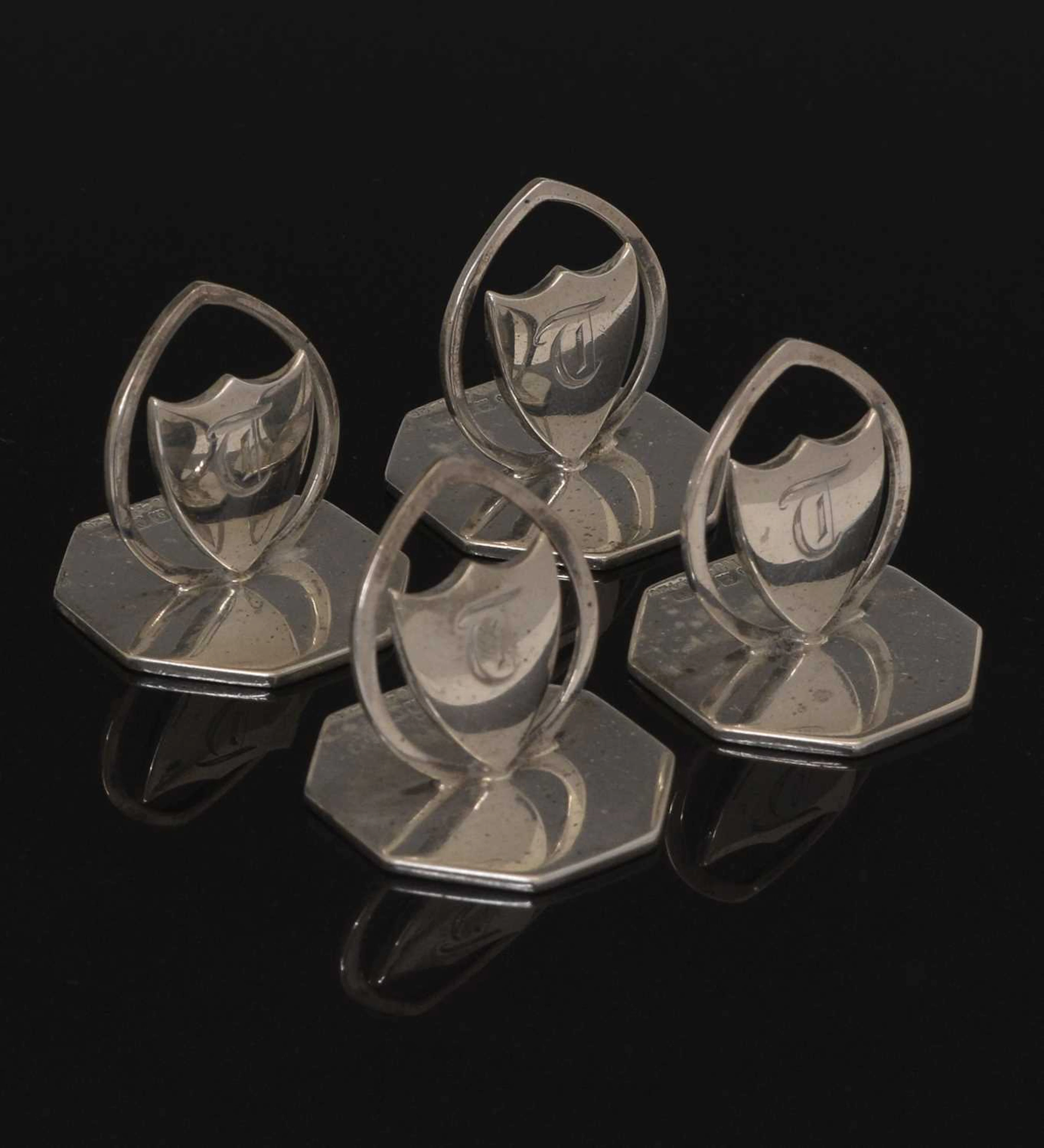 Cased set of four George V silver menu holders with shield design
