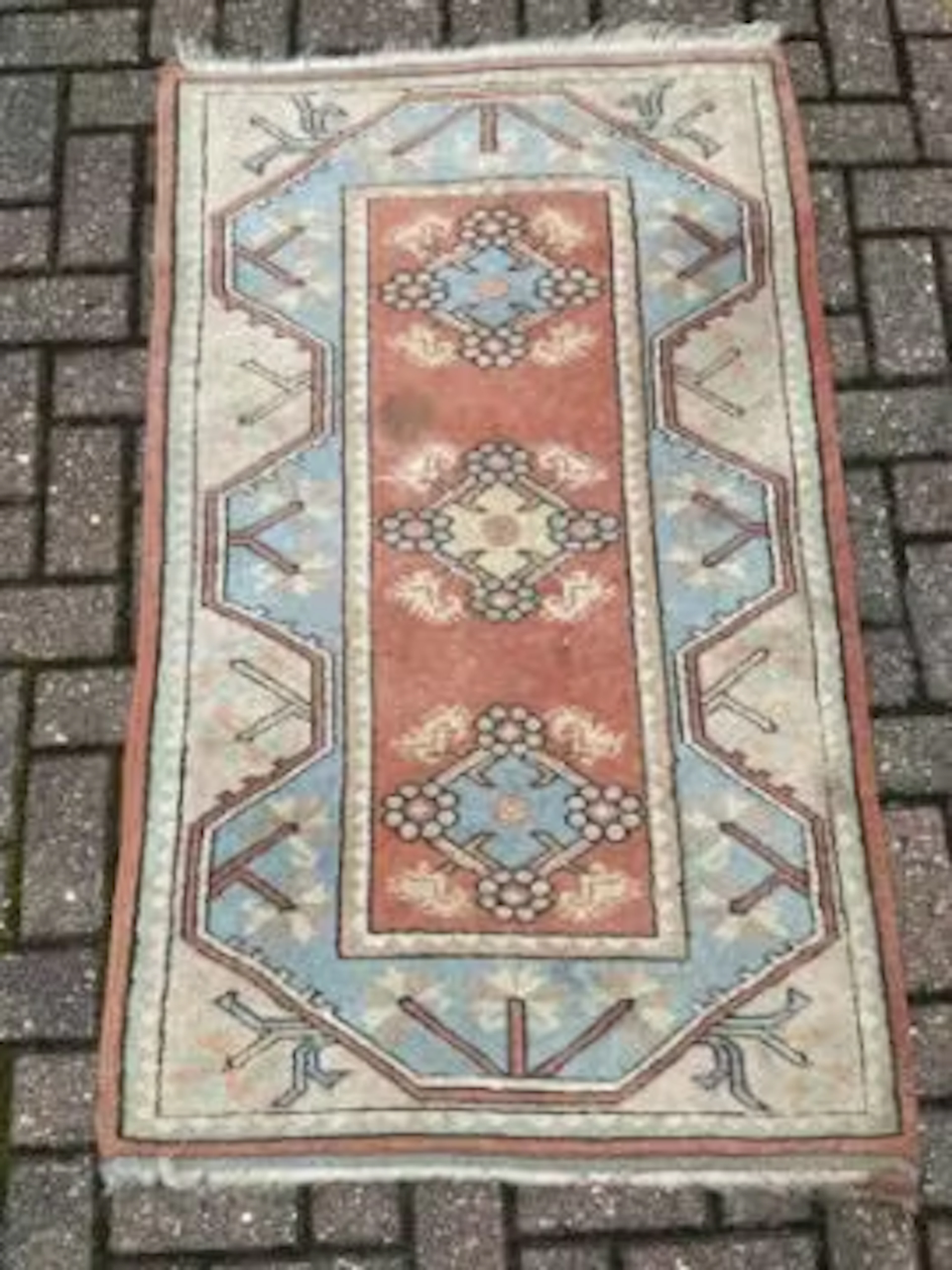 A Turkish rug with repeating flowerhead medallions on a terracotta