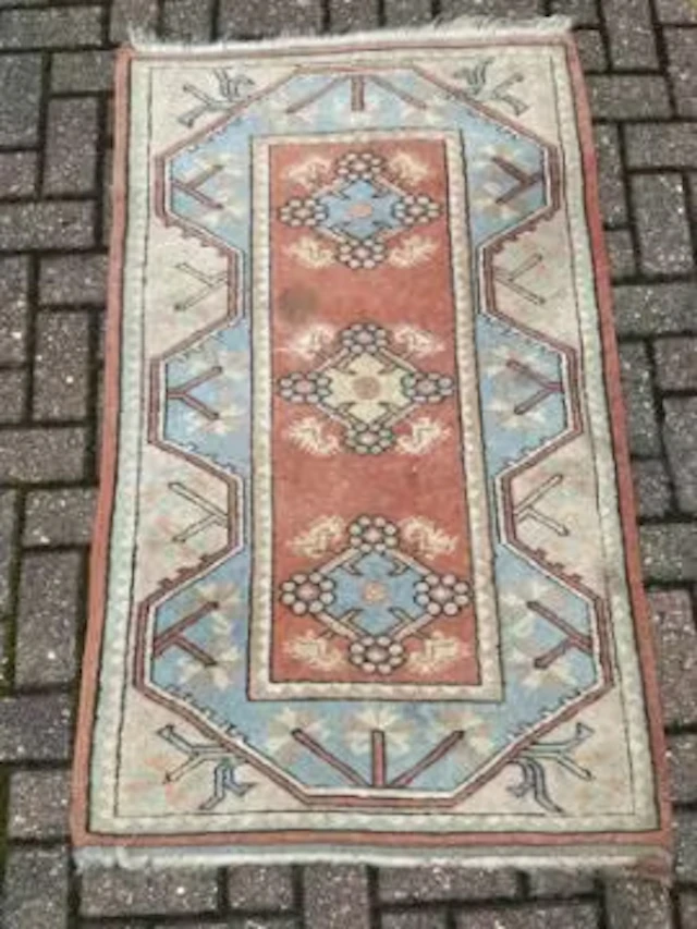 A Turkish rug with repeating flowerhead medallions on a terracotta