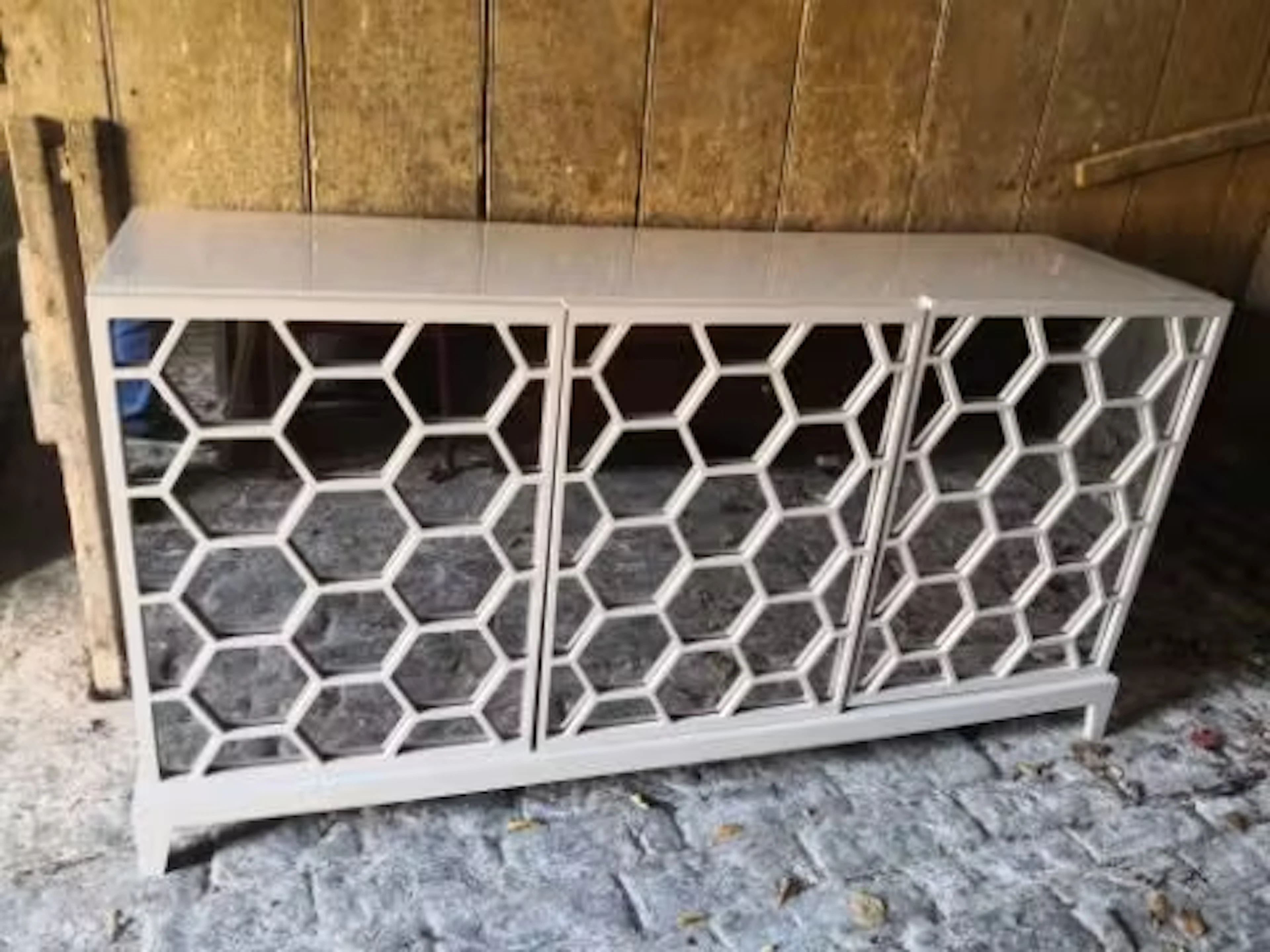 A contemporary lacquered sideboard with hexagonal mirrored panel doors.