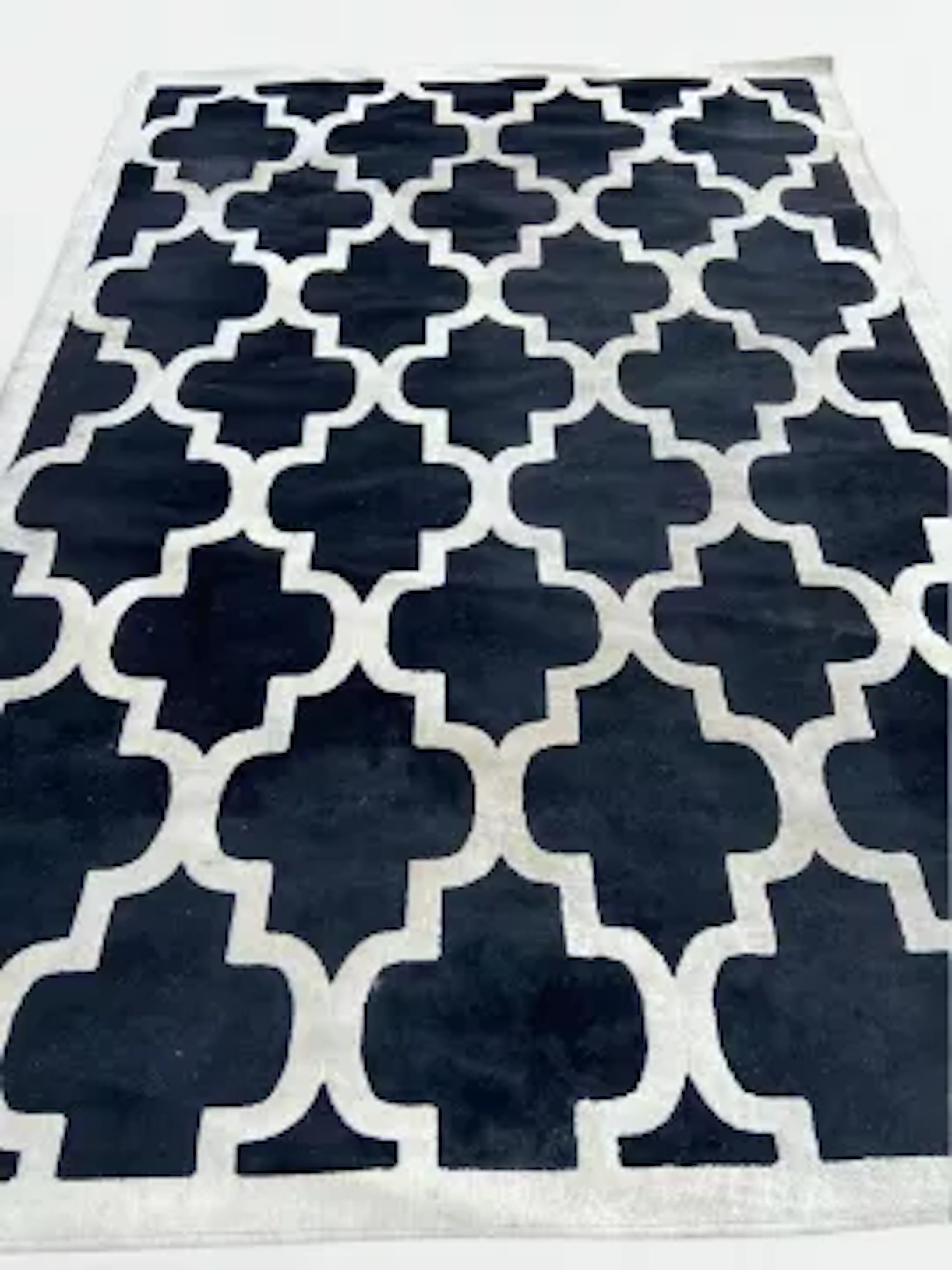 A quatrefoil trellis design carpet with ivory pattern on a black ground.