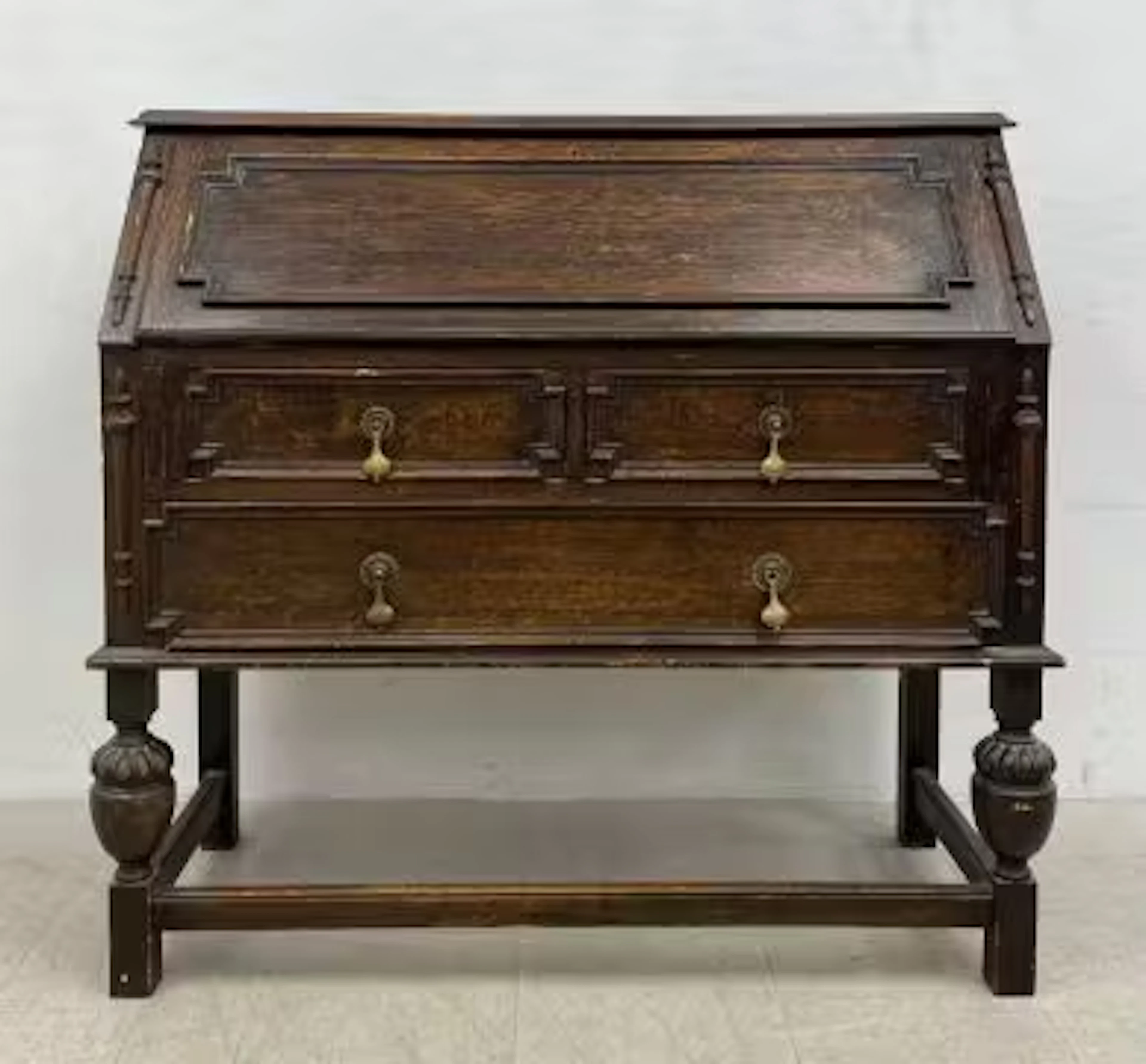 A 20th century Jacobean style oak bureau having a panelled fall front