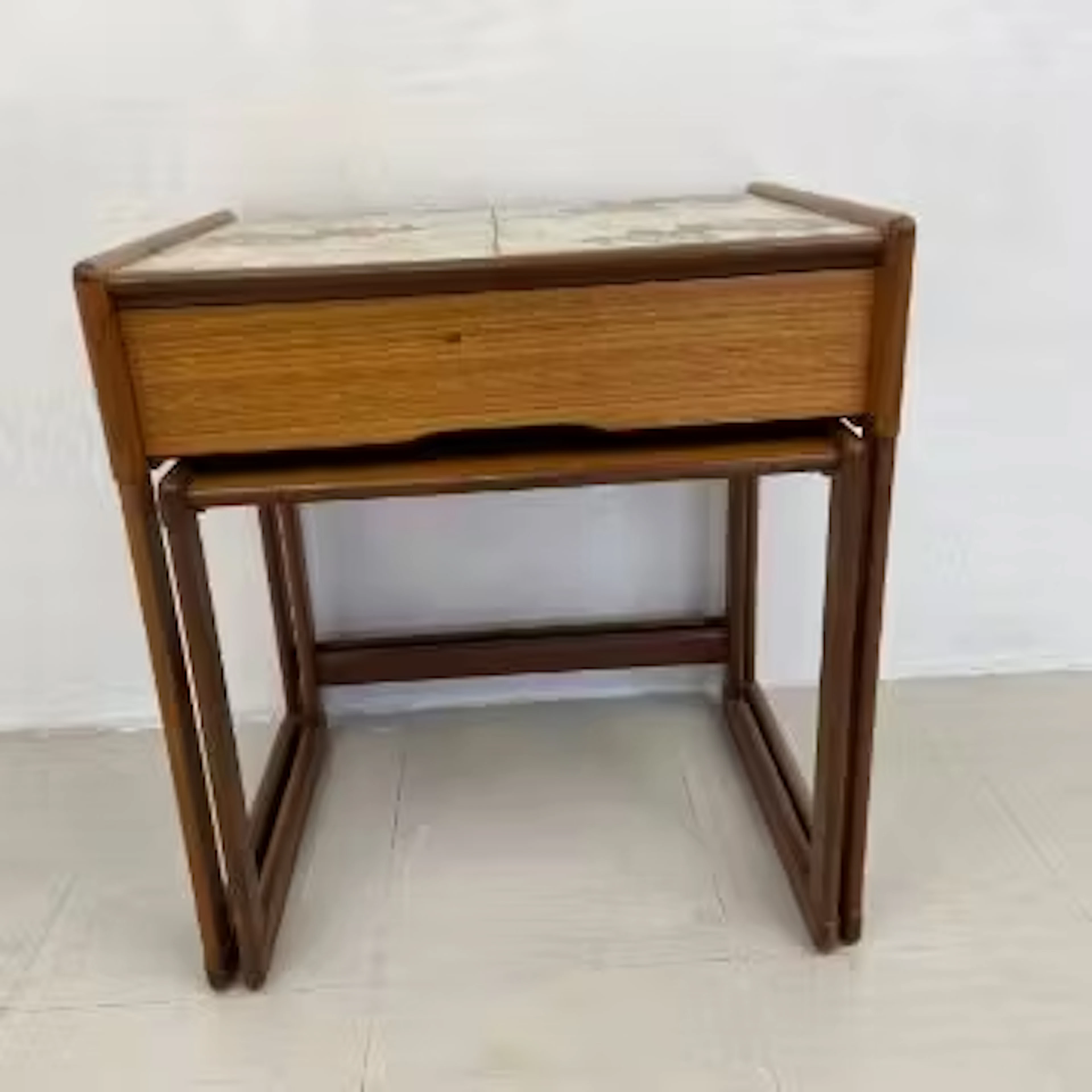 A nest of two mid-century teak occasional tables fitted with frieze
