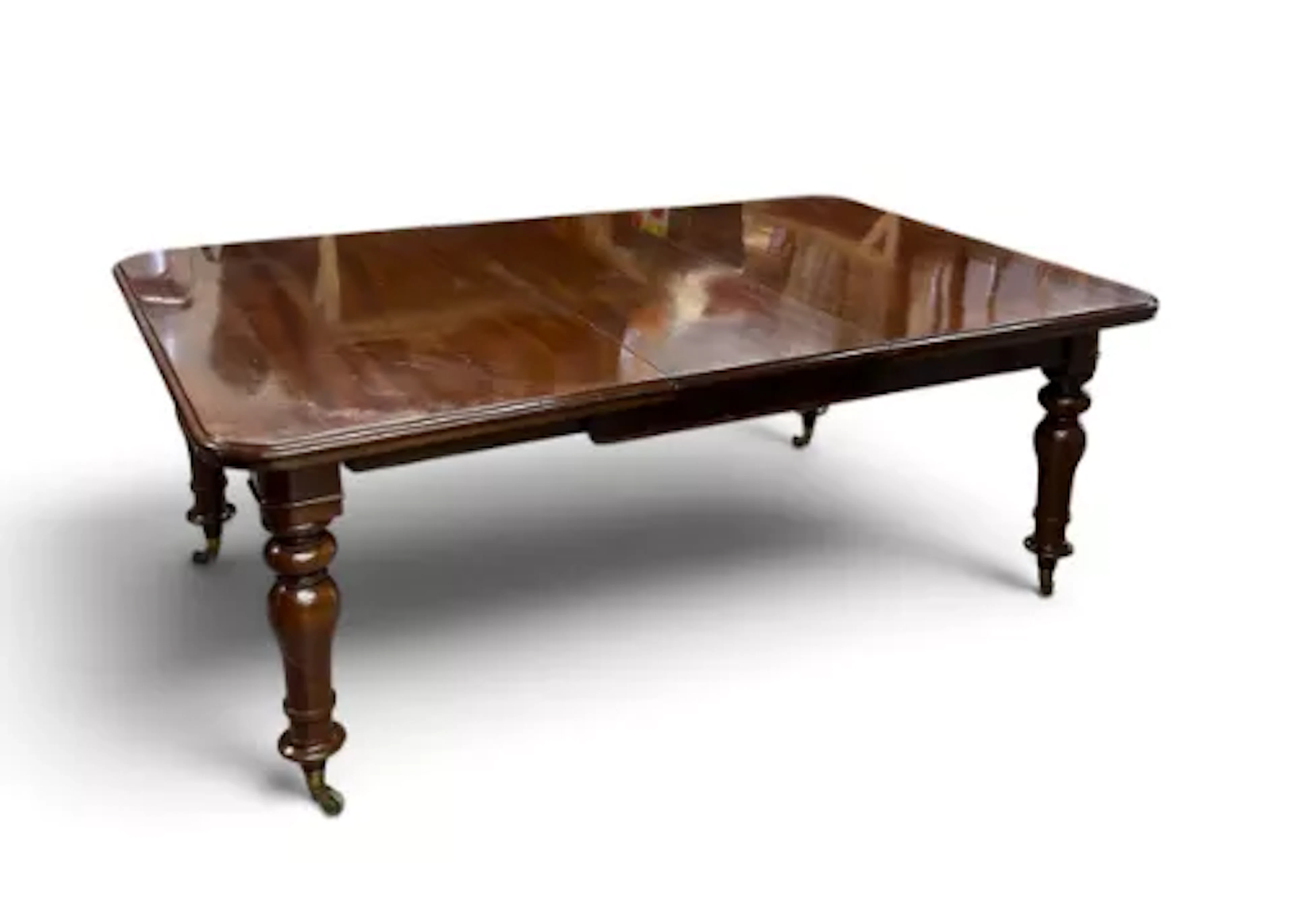 A 19th century mahogany extending dining table, turned legs on brass