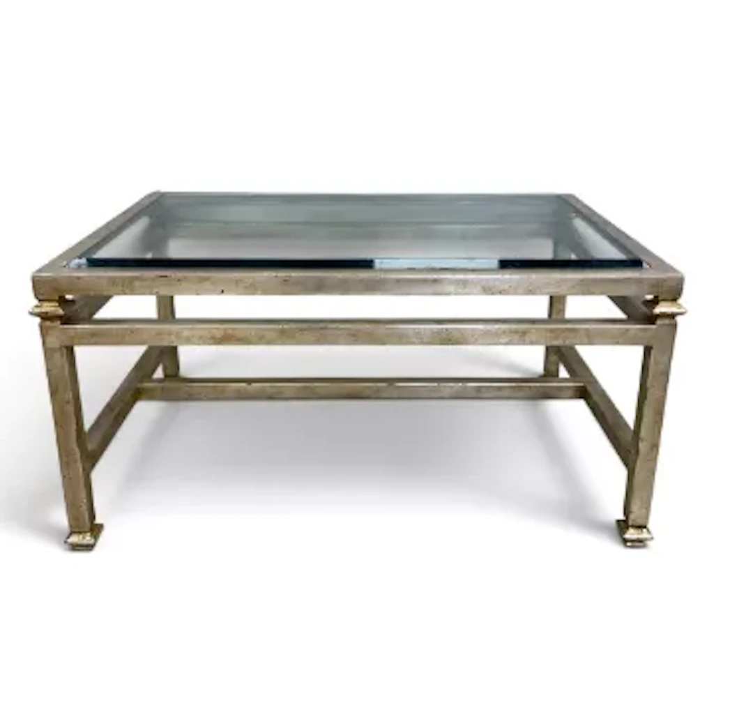 A contemporary coffee table with plate glass top on a silvered metal