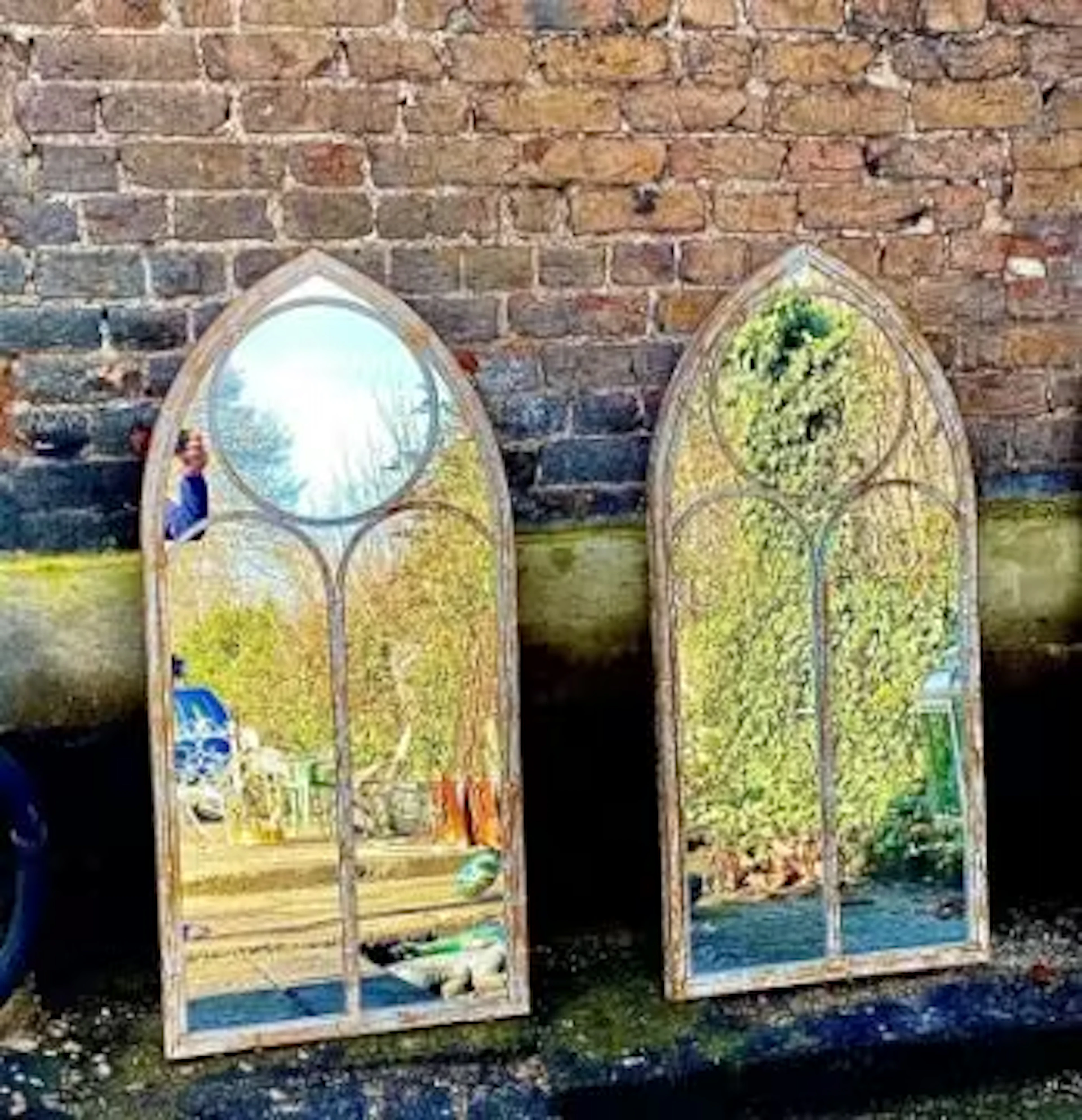 A pair of metal framed mirrors of arched Gothic form. 122x56cm.