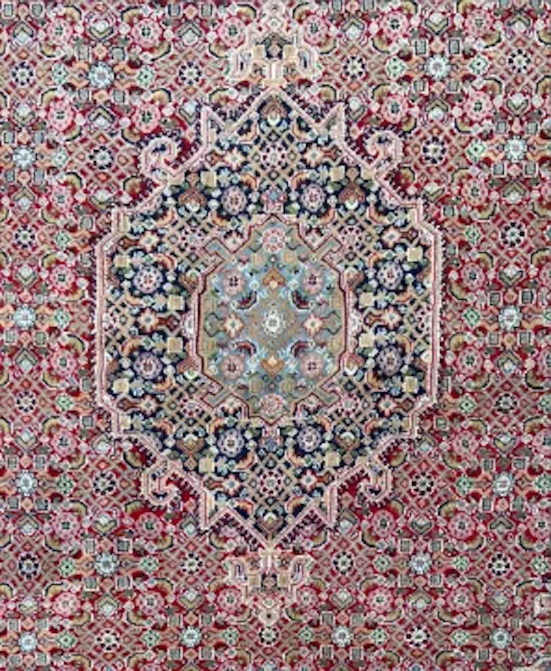 A Kazak carpet with a central lozenge medallion on a burgundy field