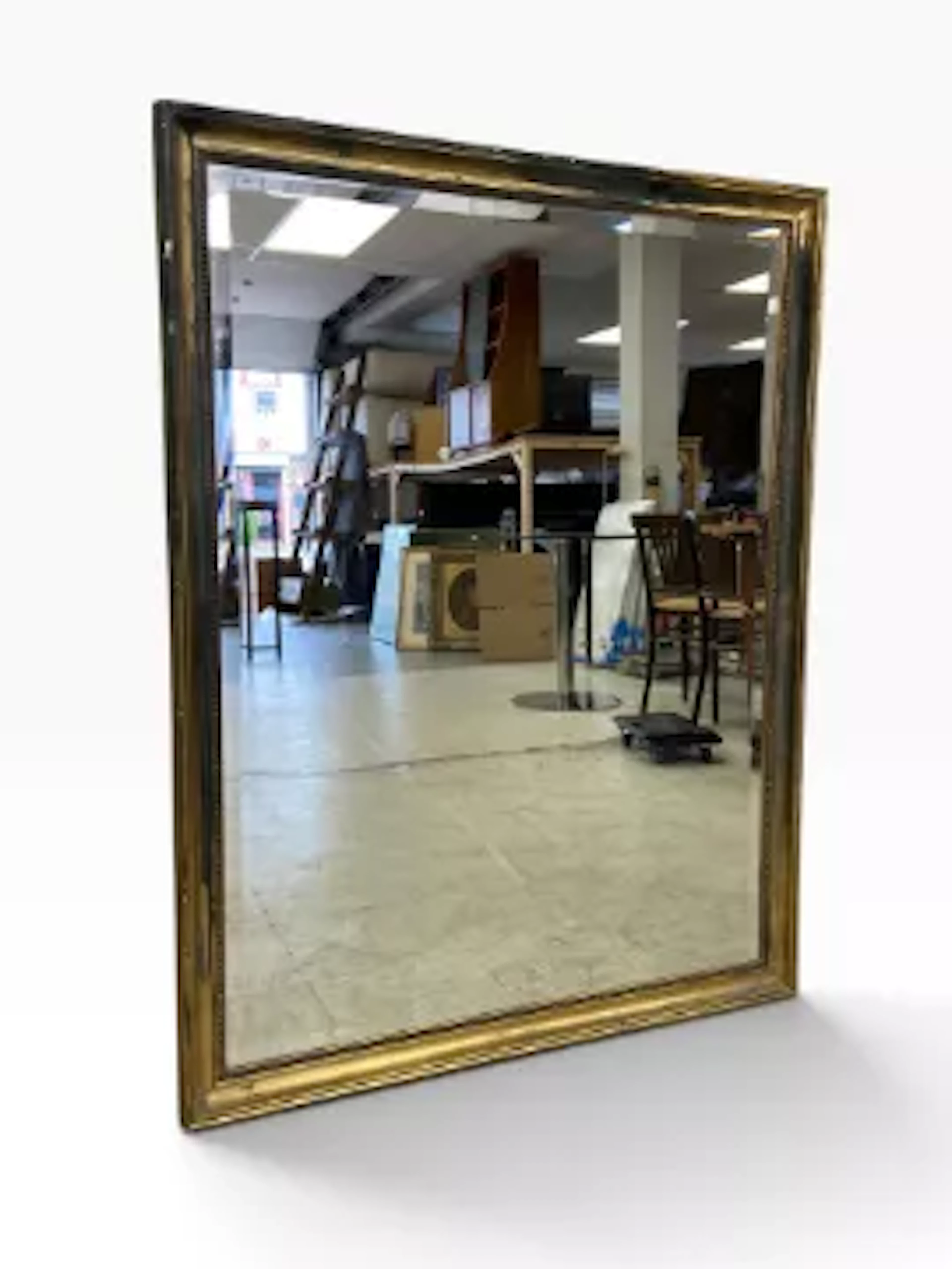 A large wall mirror with bevelled plate in distressed gilt frame.